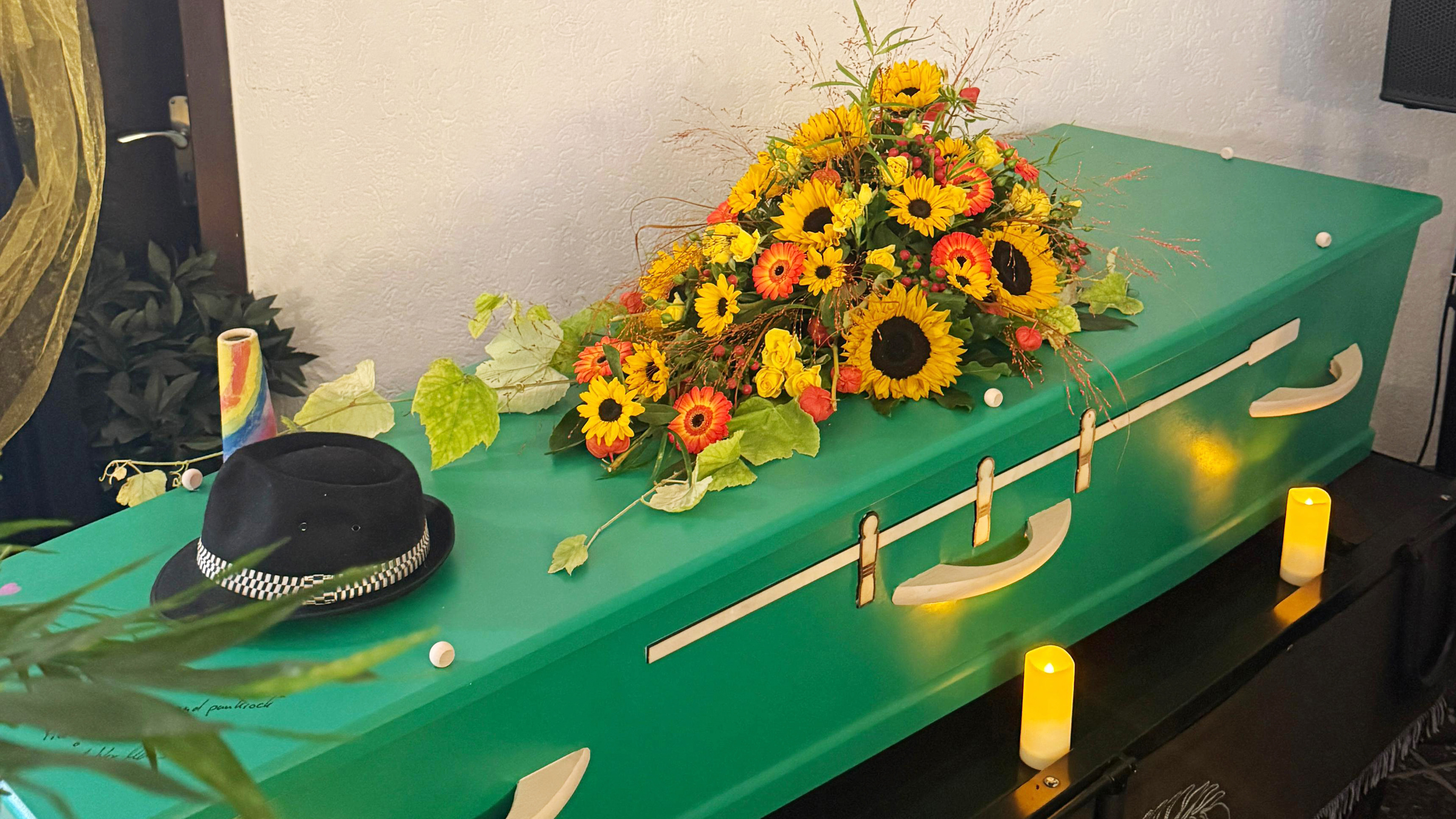 Bild eines gr&uuml;nen Sargs mit Blumen 