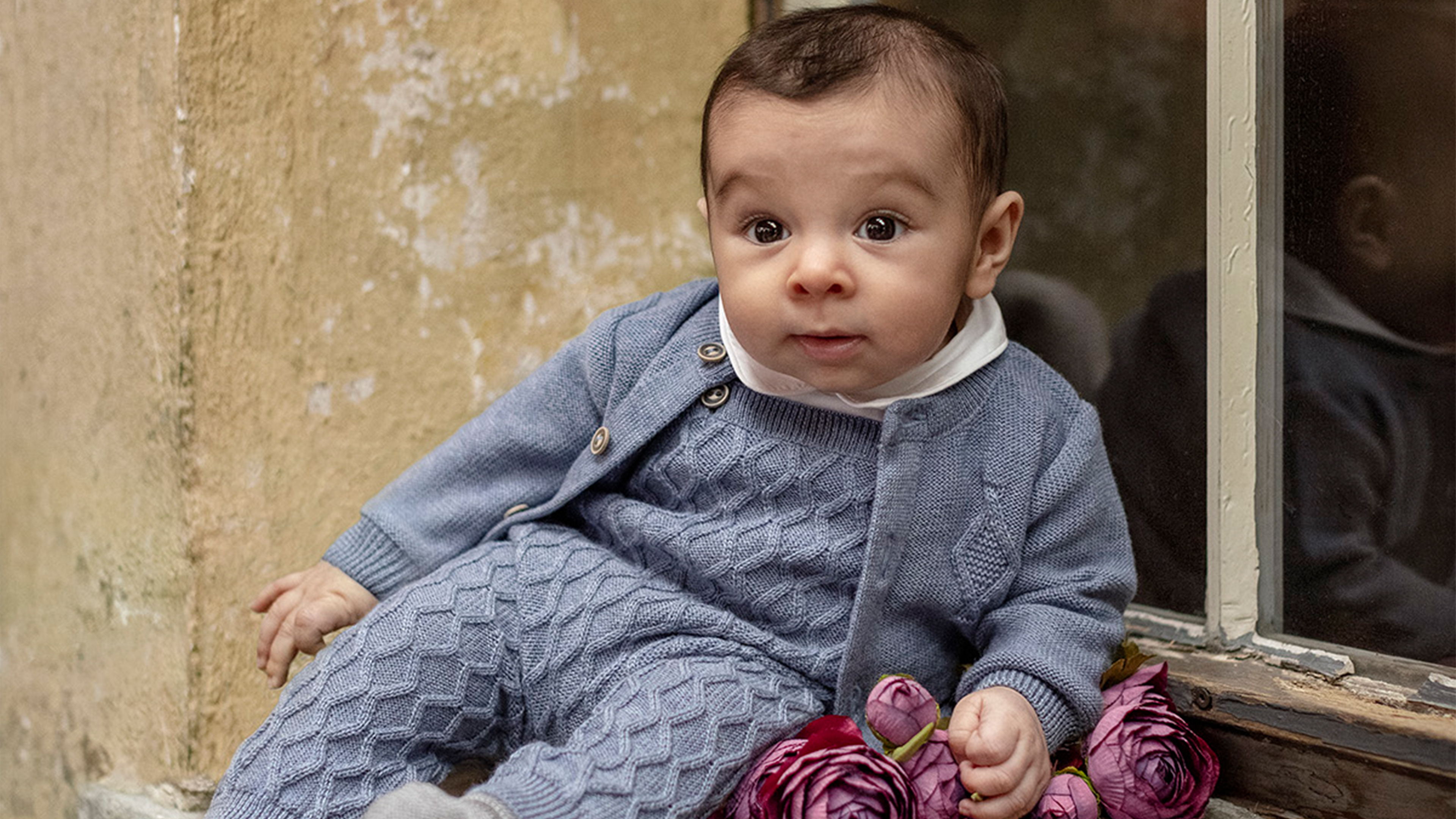 Baby mit blauer grauer Strickkleidung