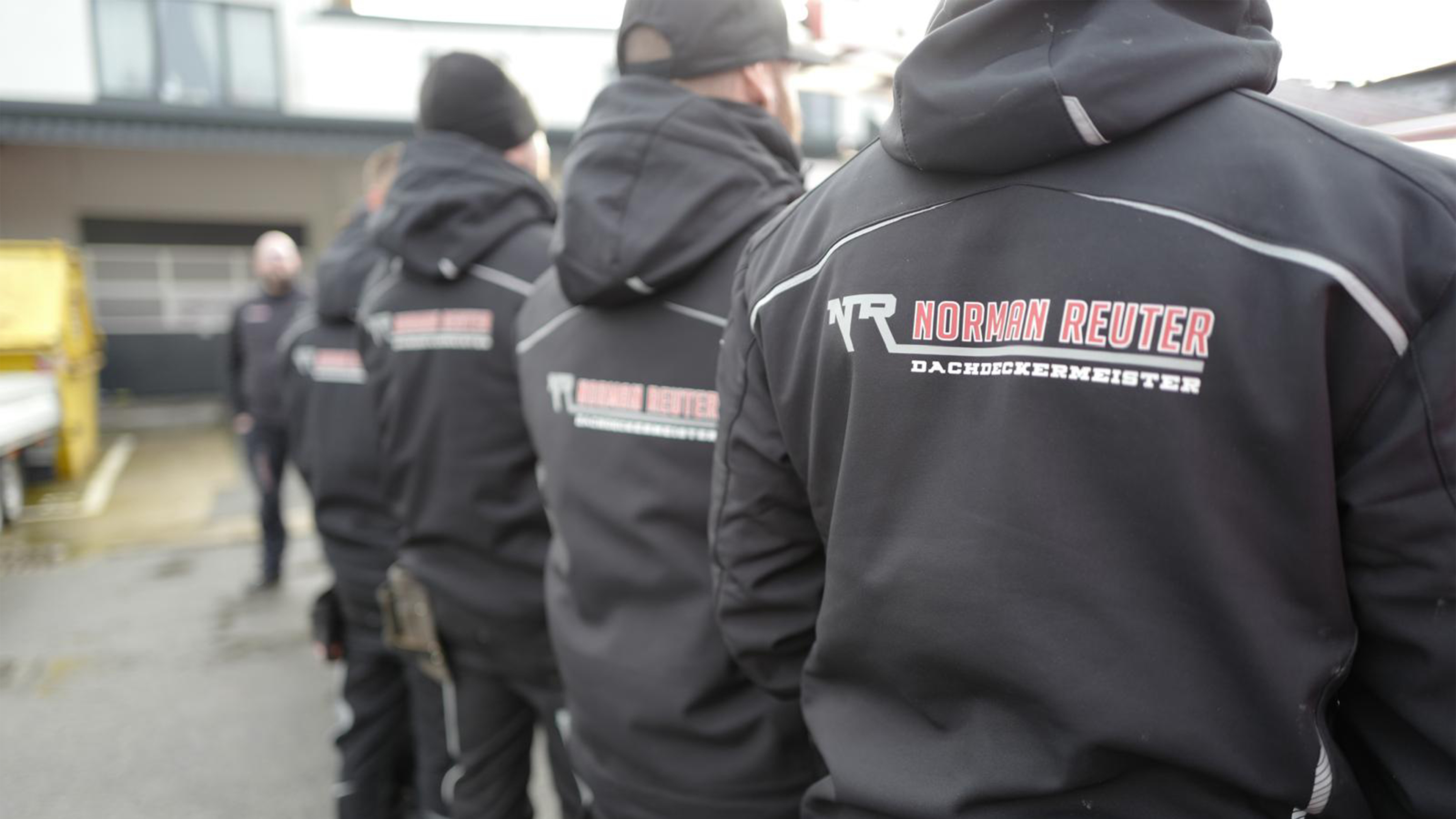 mehrere M&auml;nner stehen mit dem R&uuml;cken zur Kamera