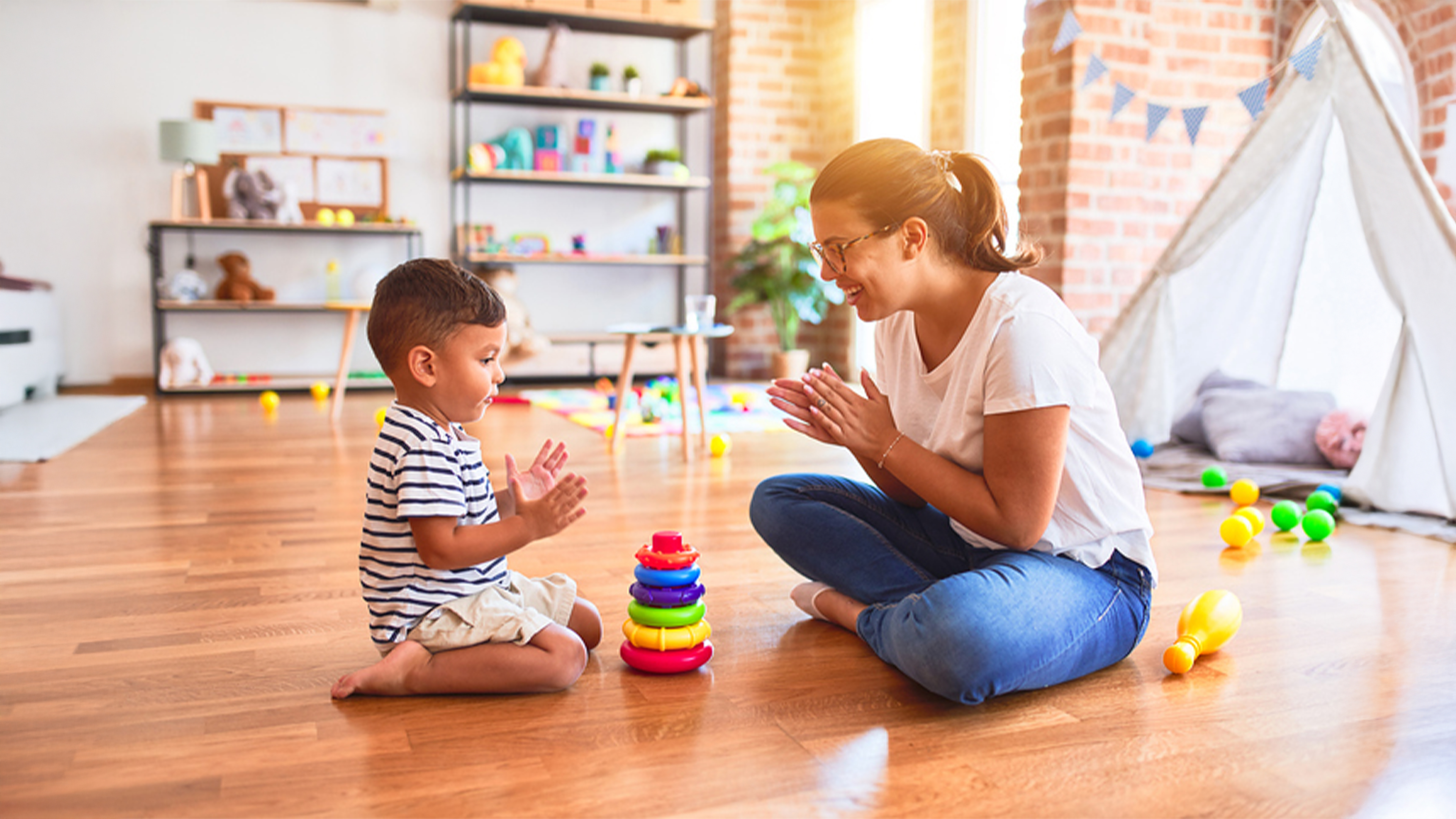 Kinderbetreuer-/in mit Kind im Spielzimmer 
