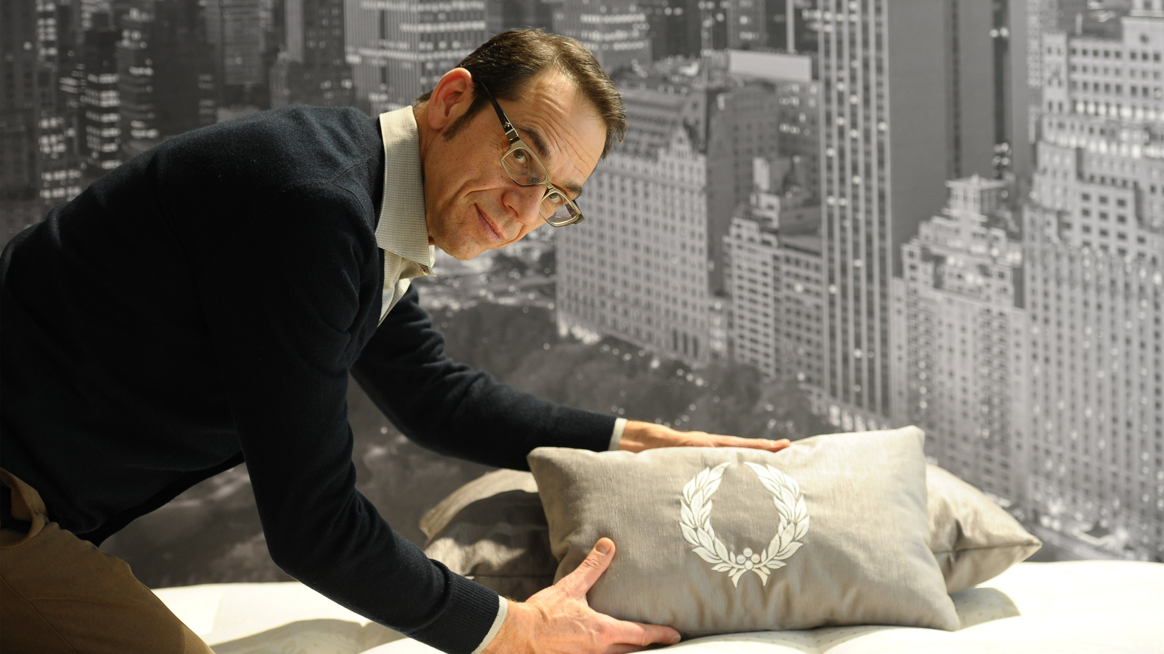 Ein Mann guckt in die Kamera und hält ein Kissen in der Hand