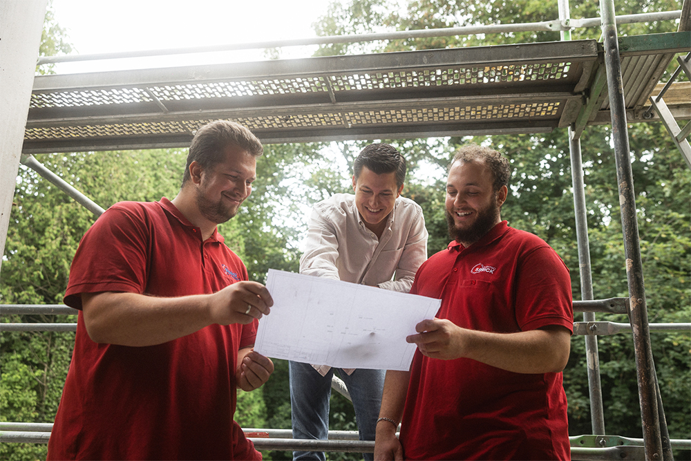 Drei Männer, die auf einen Plan schauen