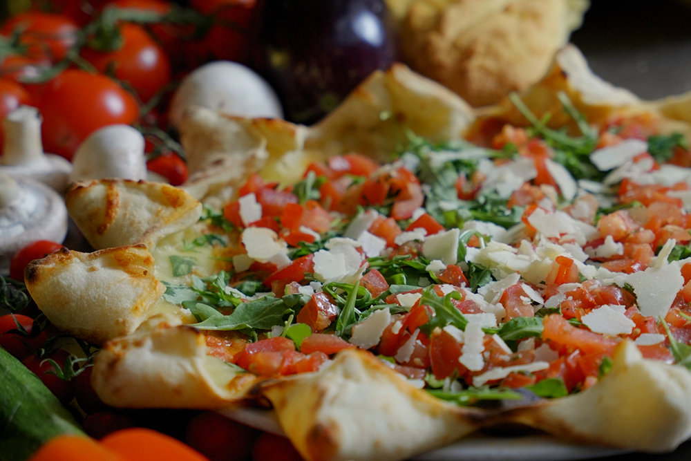 Pizza mit Rucola, Tomaten und Parmesan
