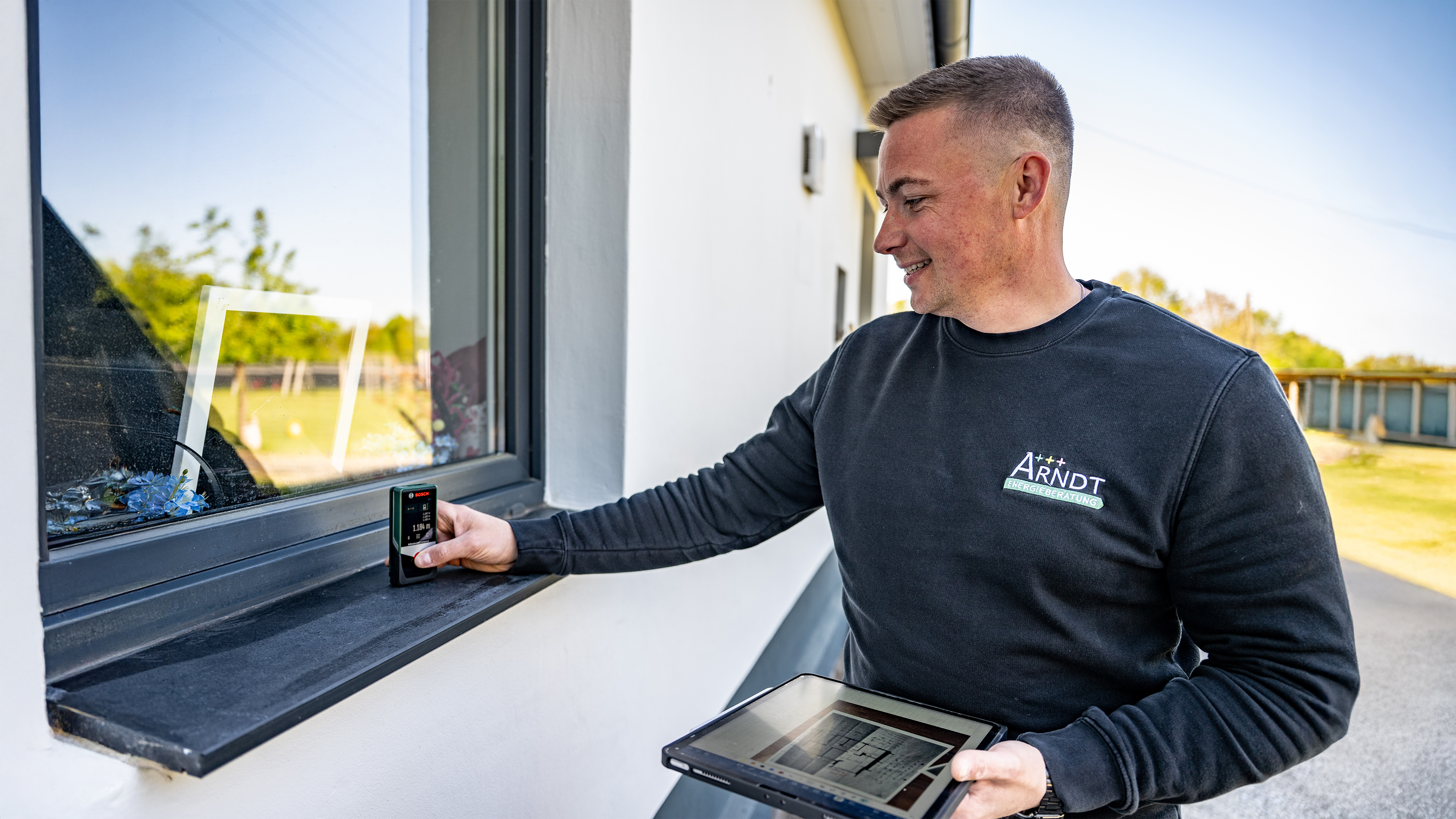 Mitarbeiter misst Fenster mit Laserentfernungsmesser.