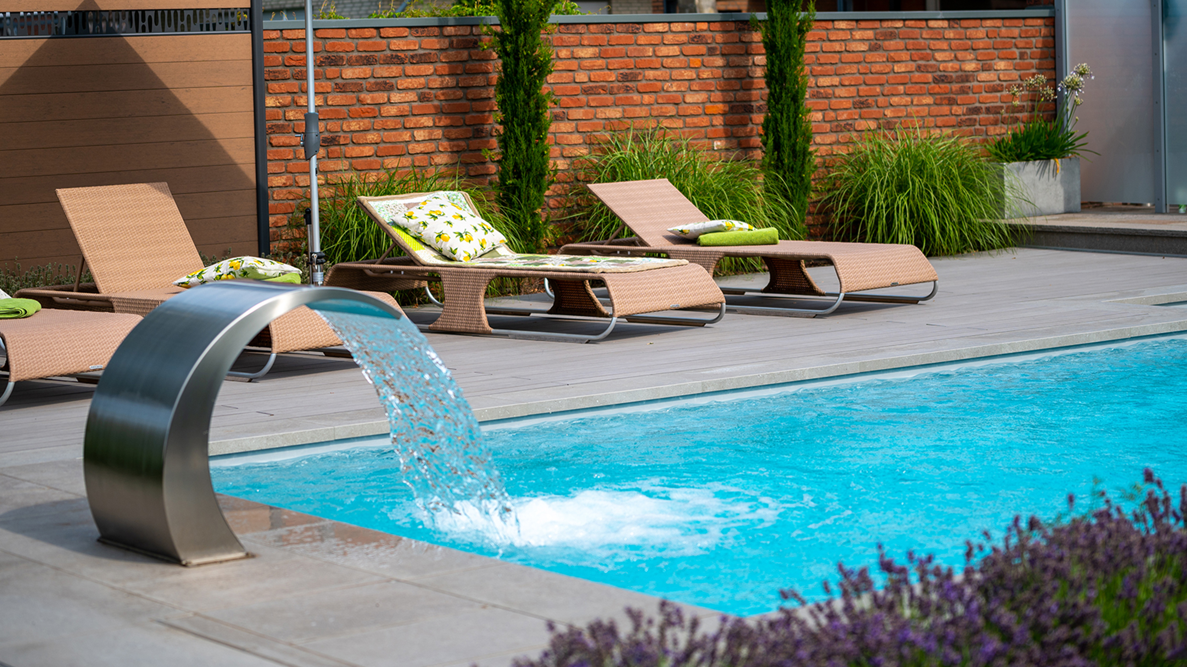 Pool mit modernem Wasserfall aus Metall mit bequemen Liegen