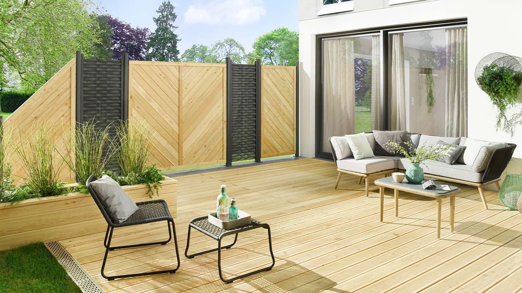 Helle Holzterrasse mit Lounge und kombiniertem Sichtschutz aus Holz und dunklen Elementen