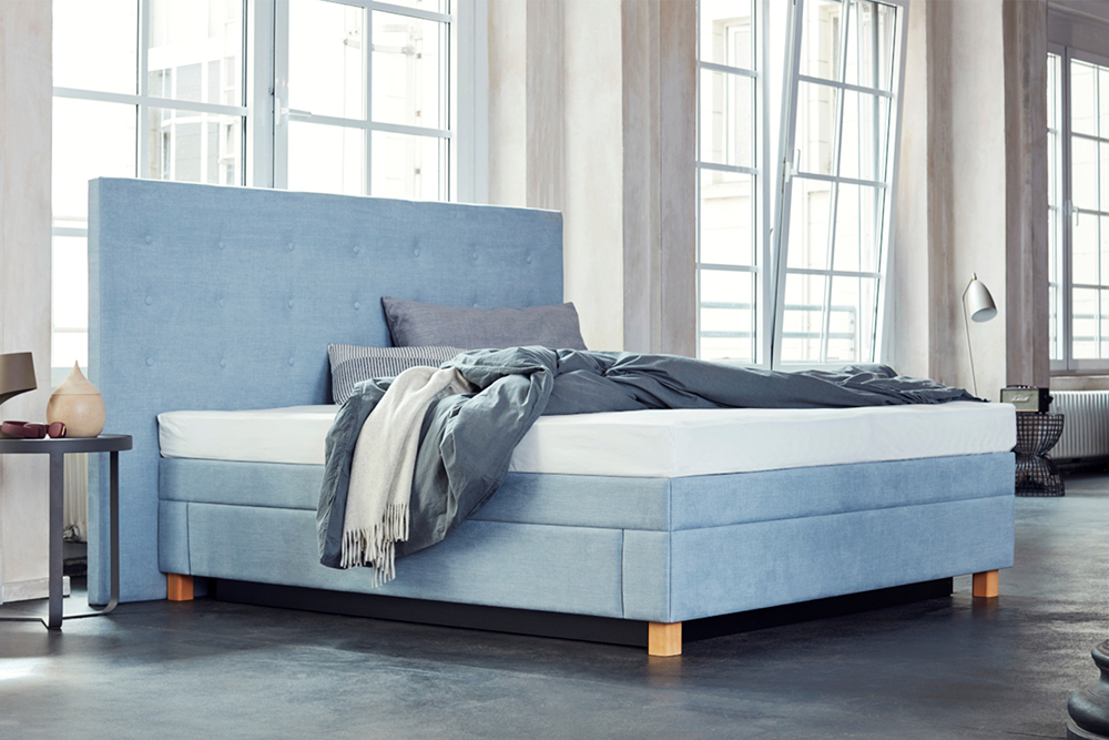 Bett aus hellblauem Stoff mit großer Rückwand