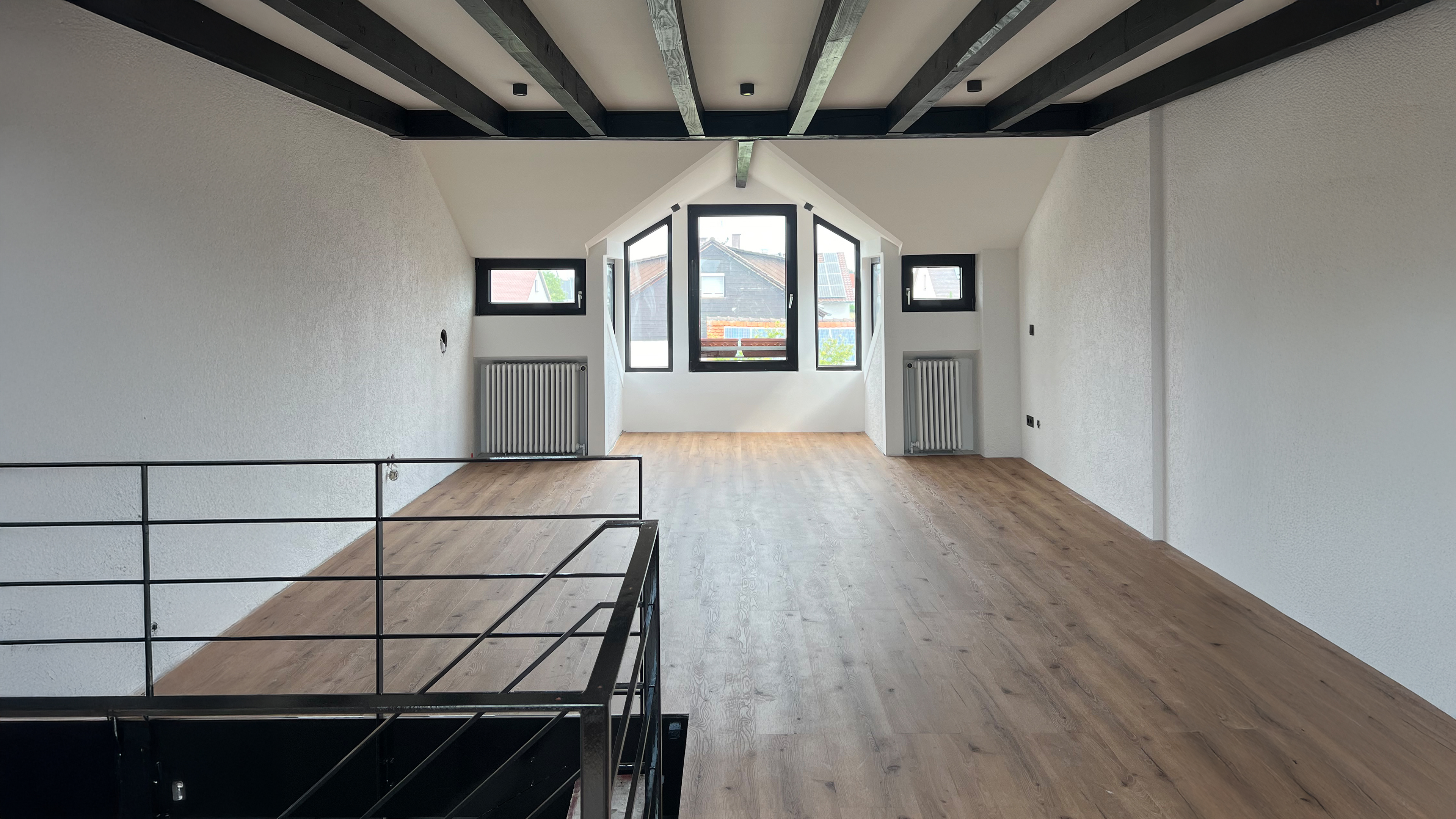 Heller, moderner Dachraum mit Holzboden und gro&szlig;en Fenstern