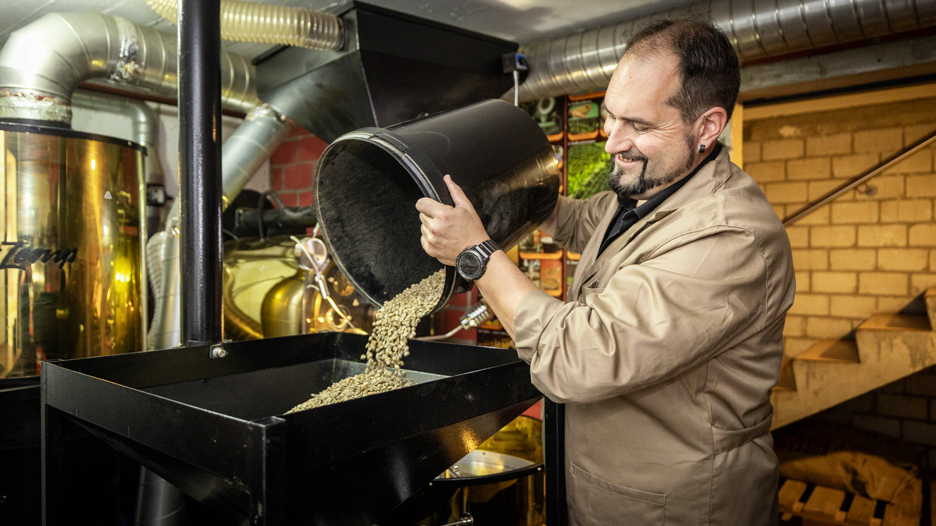 Willy Zemp füllt grüne Kaffeebohnen in eine professionelle Röstmaschine