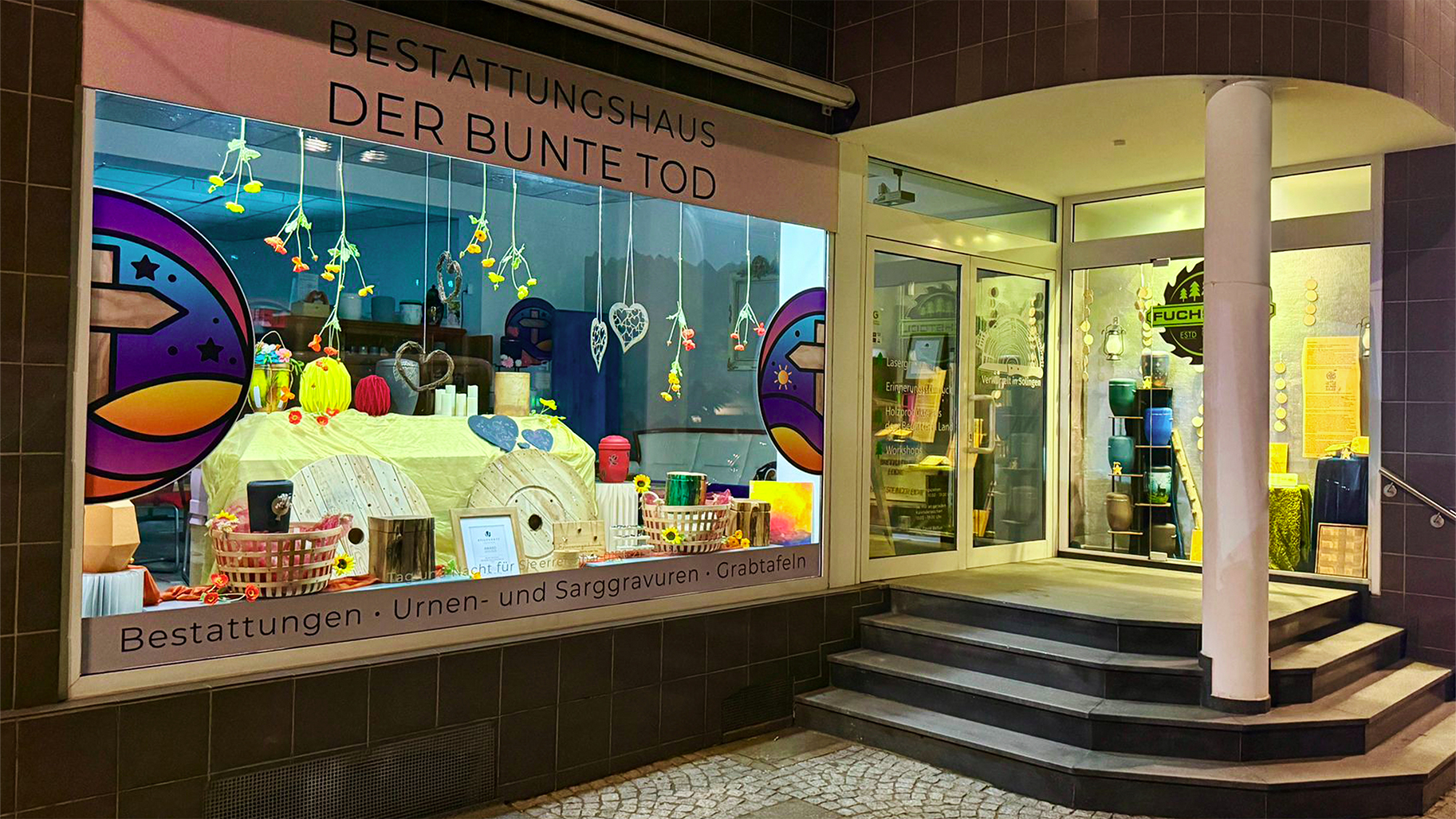 Schaufenster des Bestattungshauses Der bunte Tod in Solingen mit farbig gestalteten Urnen und Dekorationen