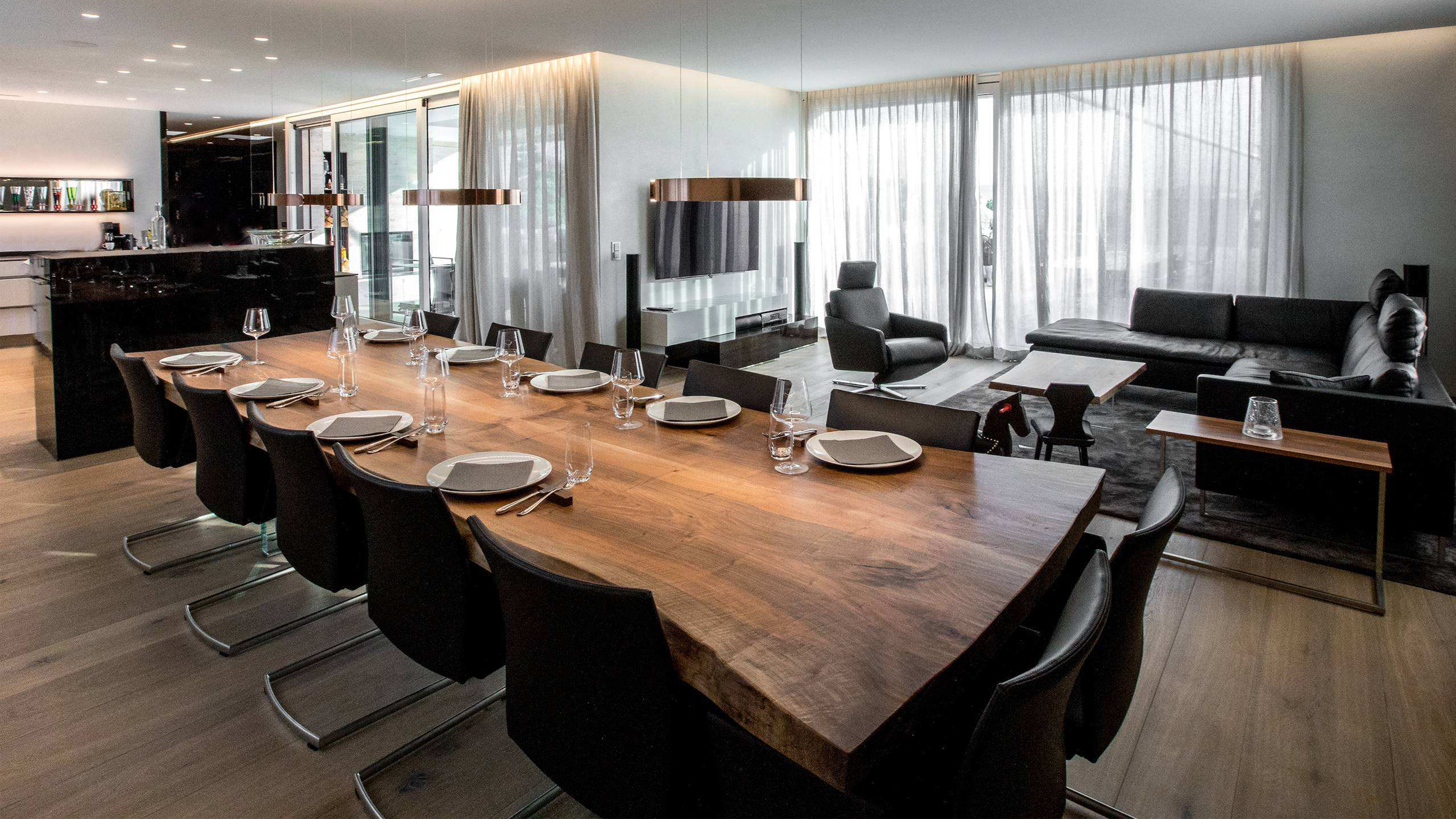 Esszimmer mit großem Holztisch und schwarzen Ledersesseln