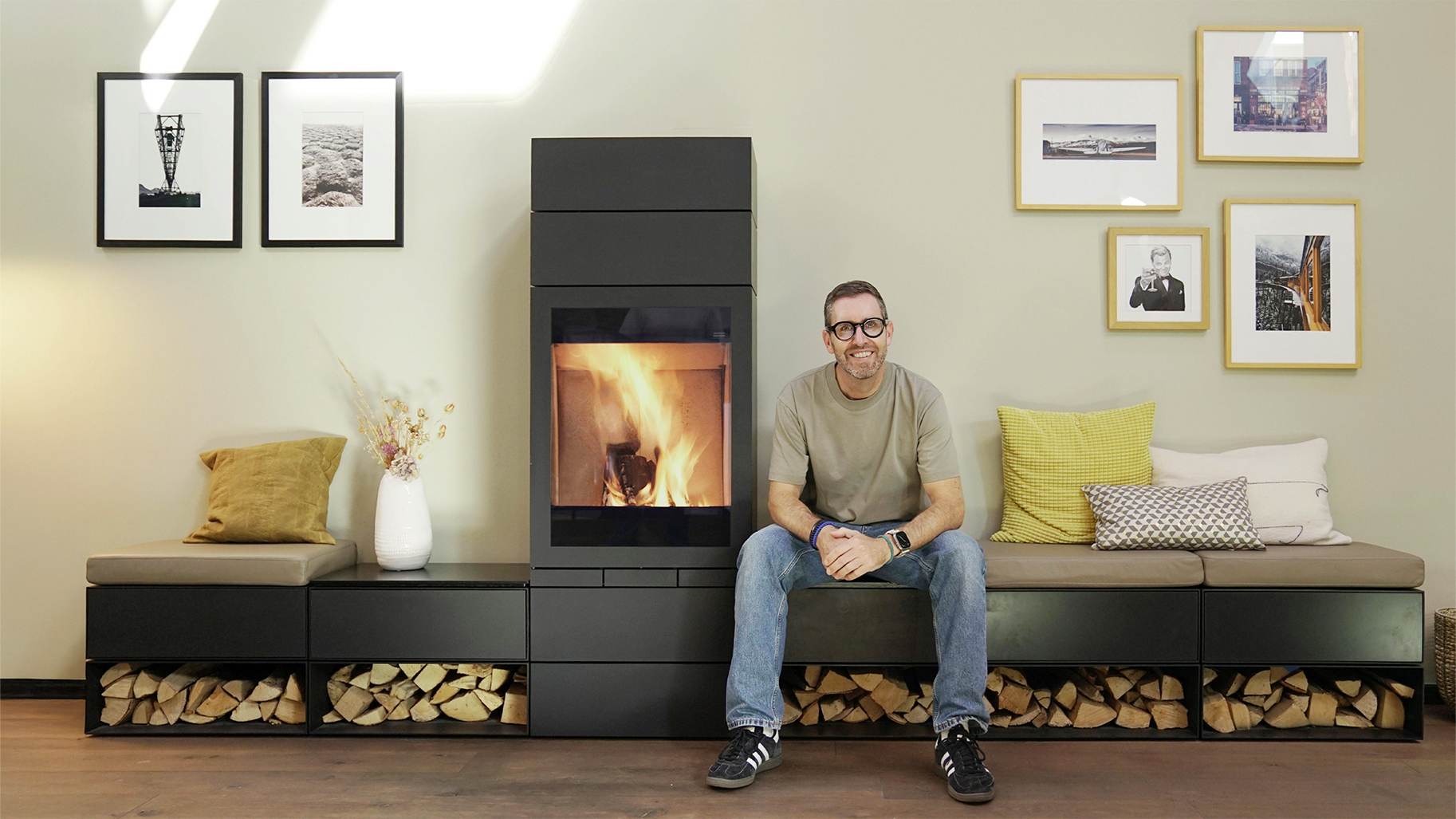 Tobias Weber vor einem modernen Kaminofen mit Sitzbank und integriertem Holzlager im Feuerloft Showroom