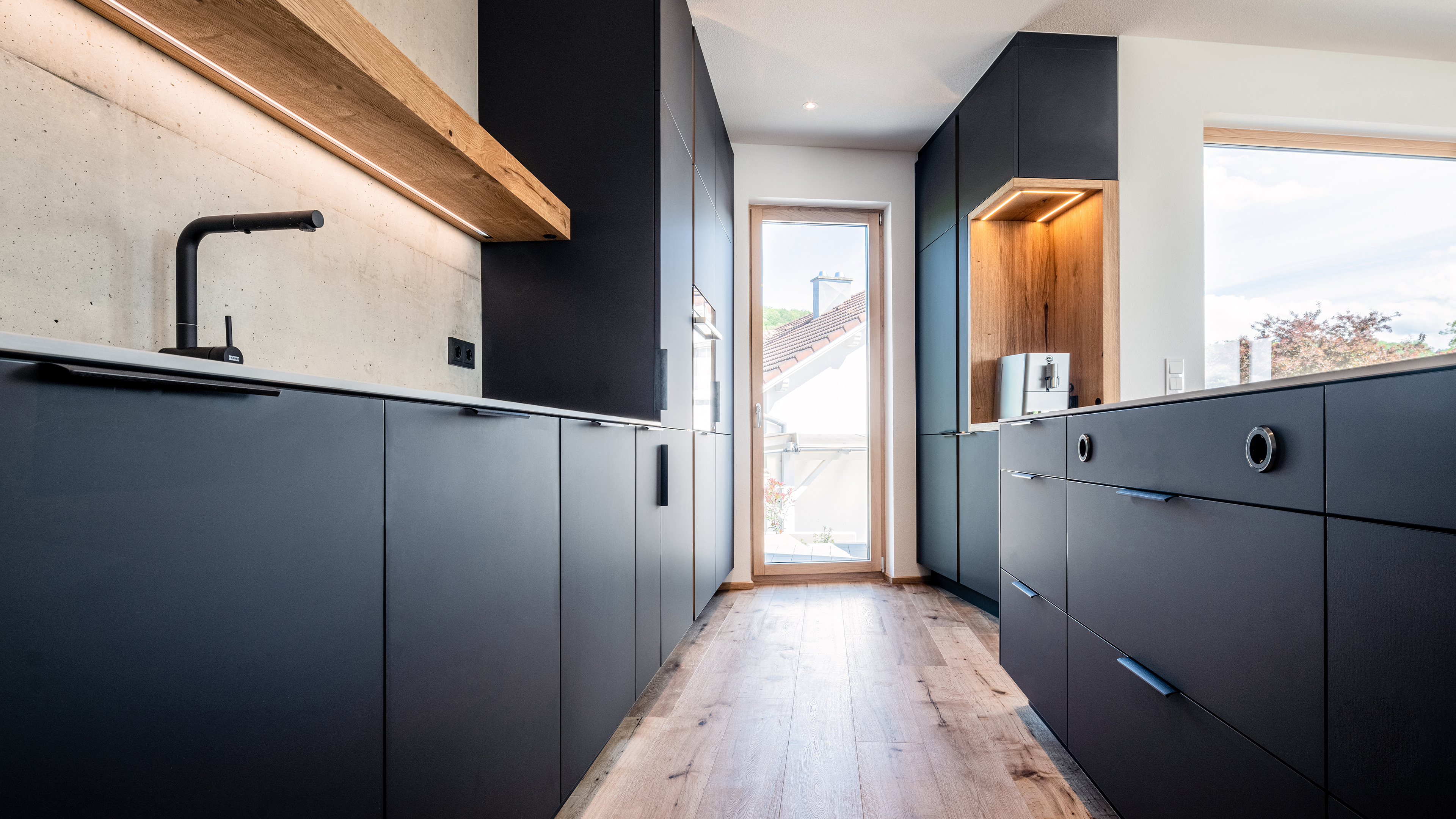 Exclusive Küche mit hochwertiger schwarzer Front und Holzelementen von Grabner Design GmbH