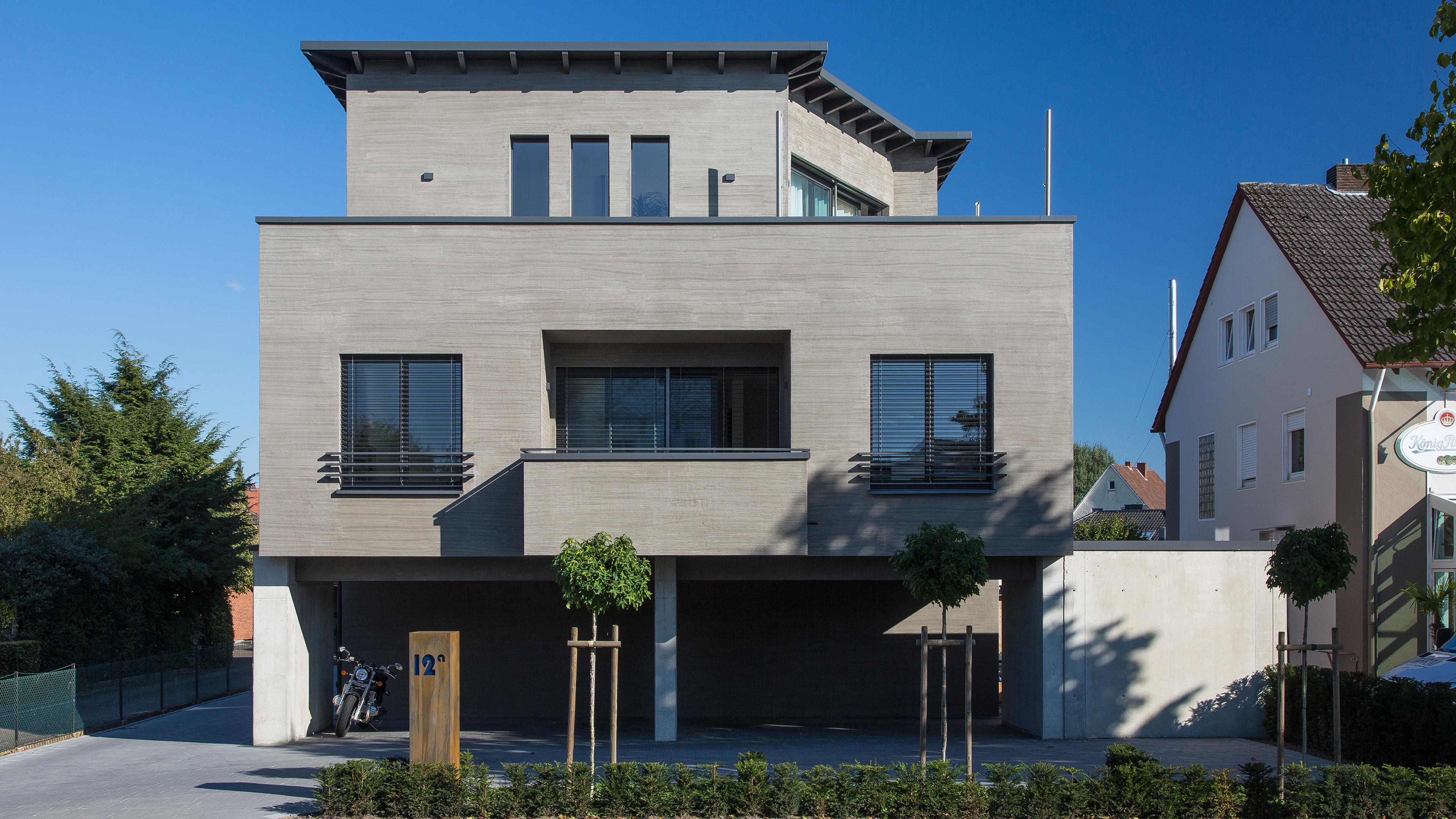 Modernes Einfamilienhaus mit graubrauner Fassade und großen Fenstern