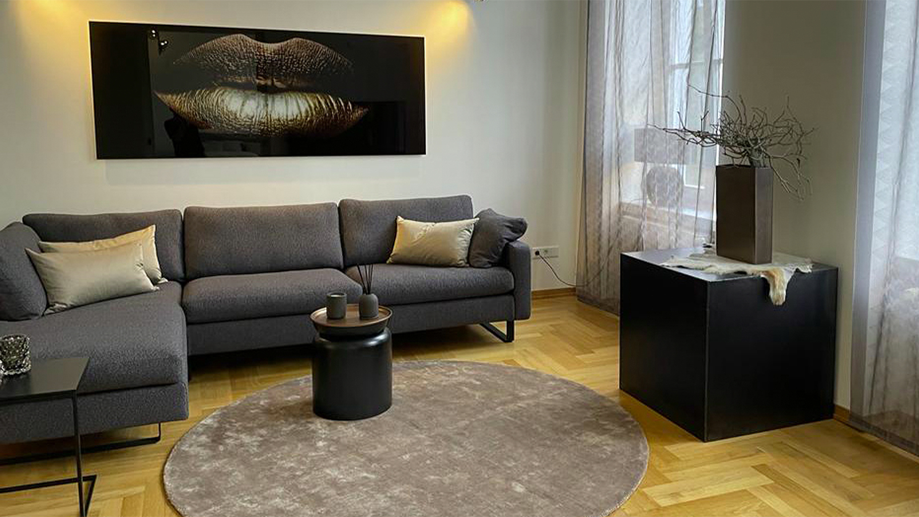 Modernes Wohnzimmer-Design von Pure Highlight: Ein graues Ecksofa kombiniert mit Parkettboden und exklusiver Wandkunst in einer Premium-Immobilie