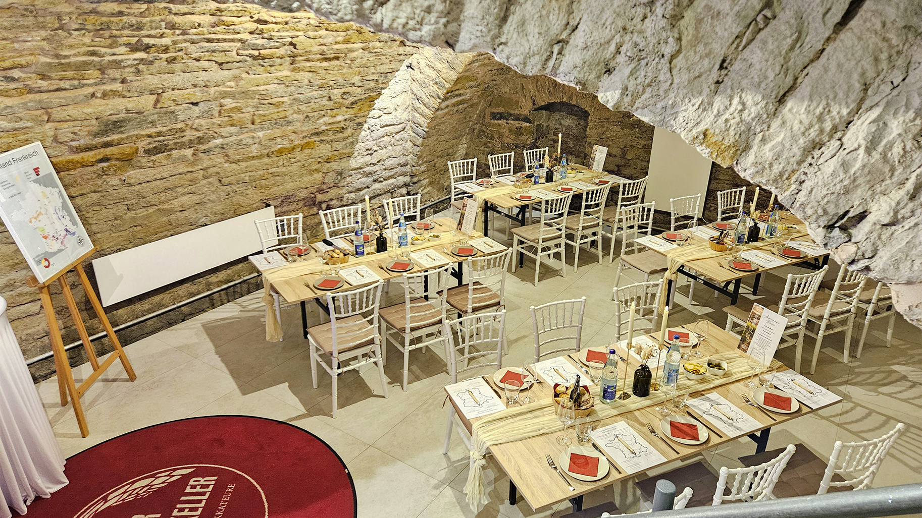 Exklusive Eventlocation in einem historischen Gew&ouml;lbekeller von Kalkbrenner Events. Das Bild zeigt festlich gedeckte Tafeln f&uuml;r ein Genuss-Event mit Fokus auf Weinverkostung und Sommelier-Expertise. Ein einladendes Ambiente, das den Wechsel vom Top-Management in die professionelle Eventgastronomie von Genusshochzwei unterstreicht.