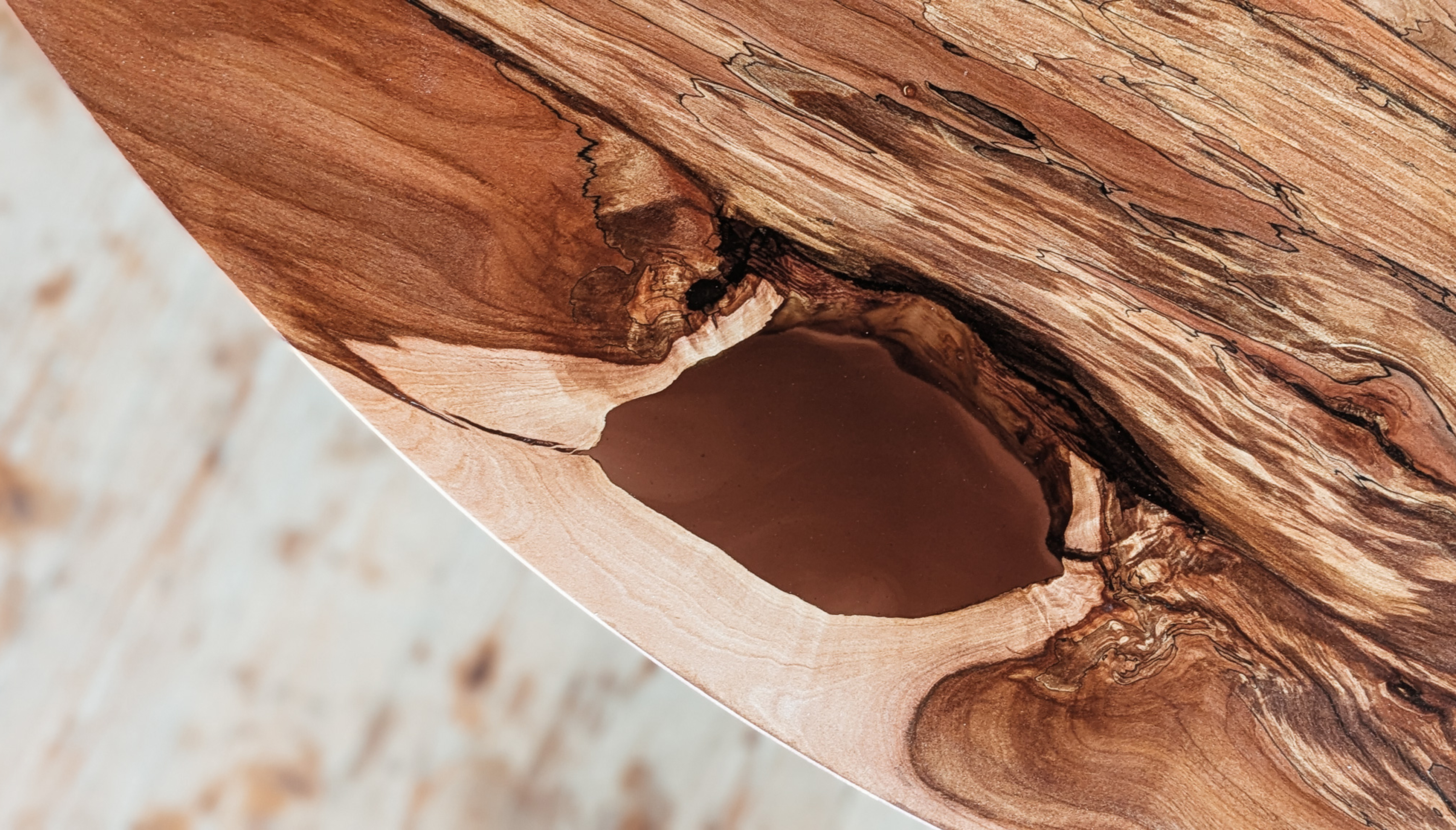 Nahaufnahme von Holzmaserung und Epoxidharz – natürliche Risse als Gestaltungselement eines Liebwerk Tisches.