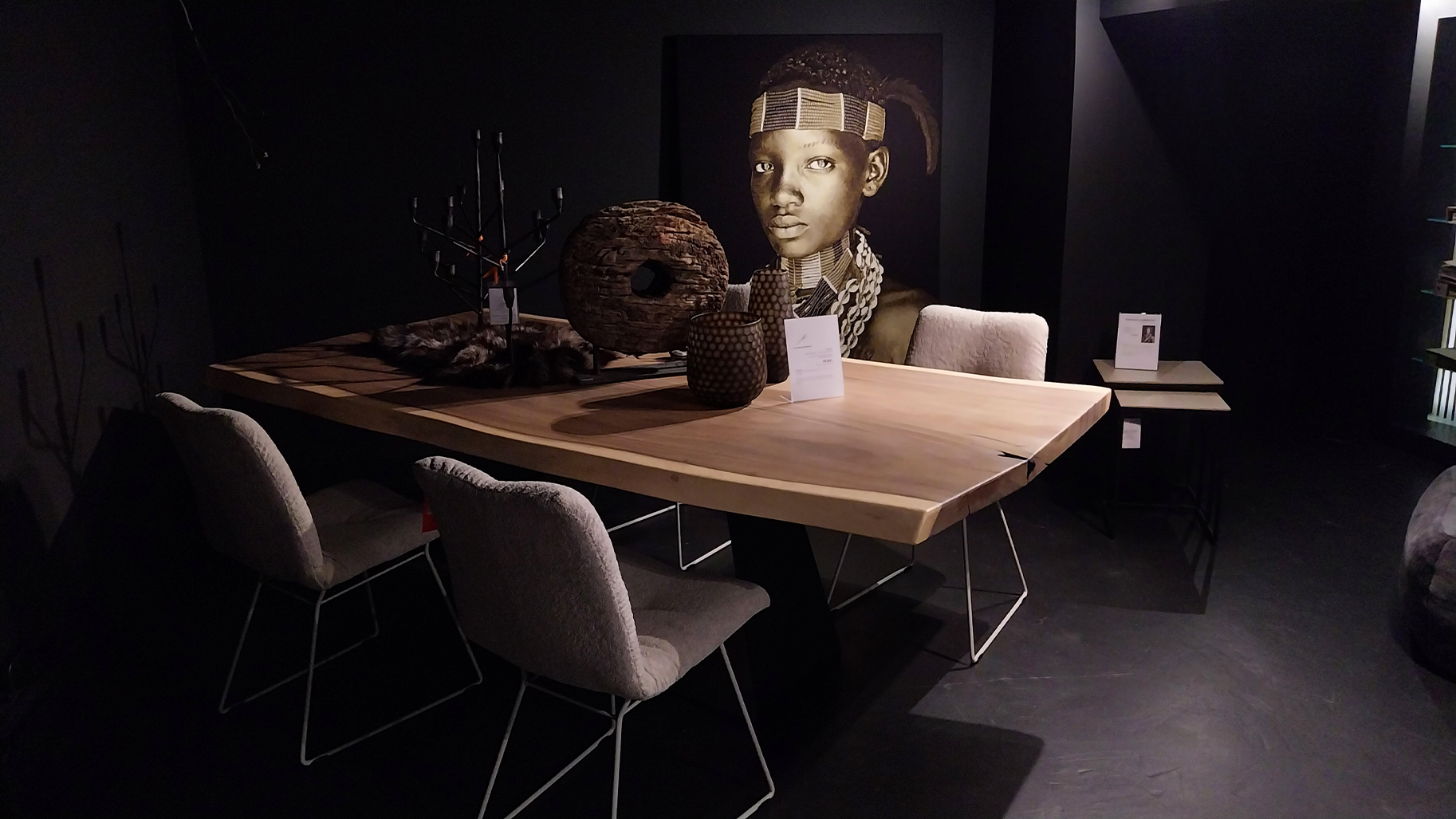 Stilvoller Essbereich mit Holztisch und St&uuml;hlen in dunklem Raum &ndash; Interior Design mit afrikanischen Einfl&uuml;ssen und dekorativen Elementen