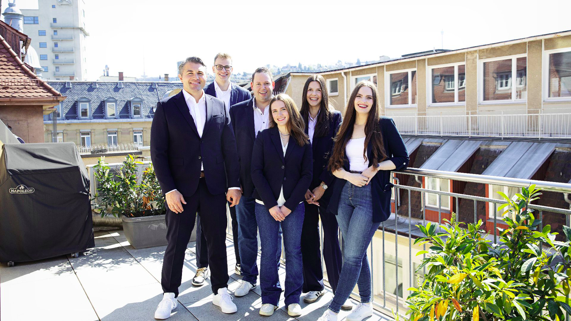 Team eines Stuttgarter Immobilienunternehmens auf einer Dachterrasse über der Innenstadt.