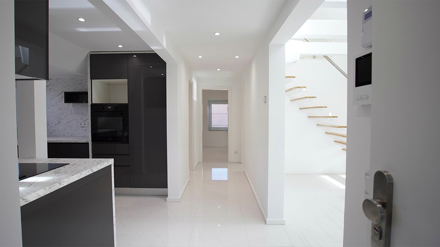 Modernisierte Wohnung mit offener Küche, hellem Flur und freitragender Holztreppe