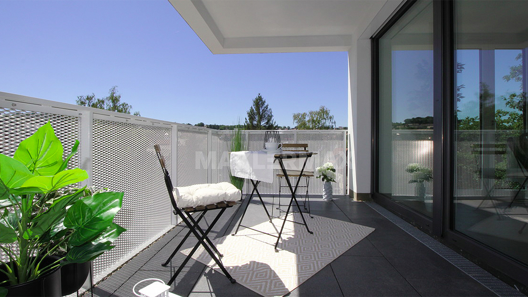 Sonniger Balkon mit Sitzgruppe, Pflanzen und großflächiger Glasfront