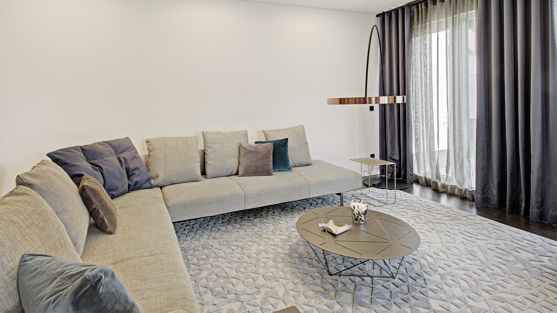 Großzügiges weißes modulares Sofa mit runden Polstern und gepolstertem Hocker in einer hellen Ausstellung.