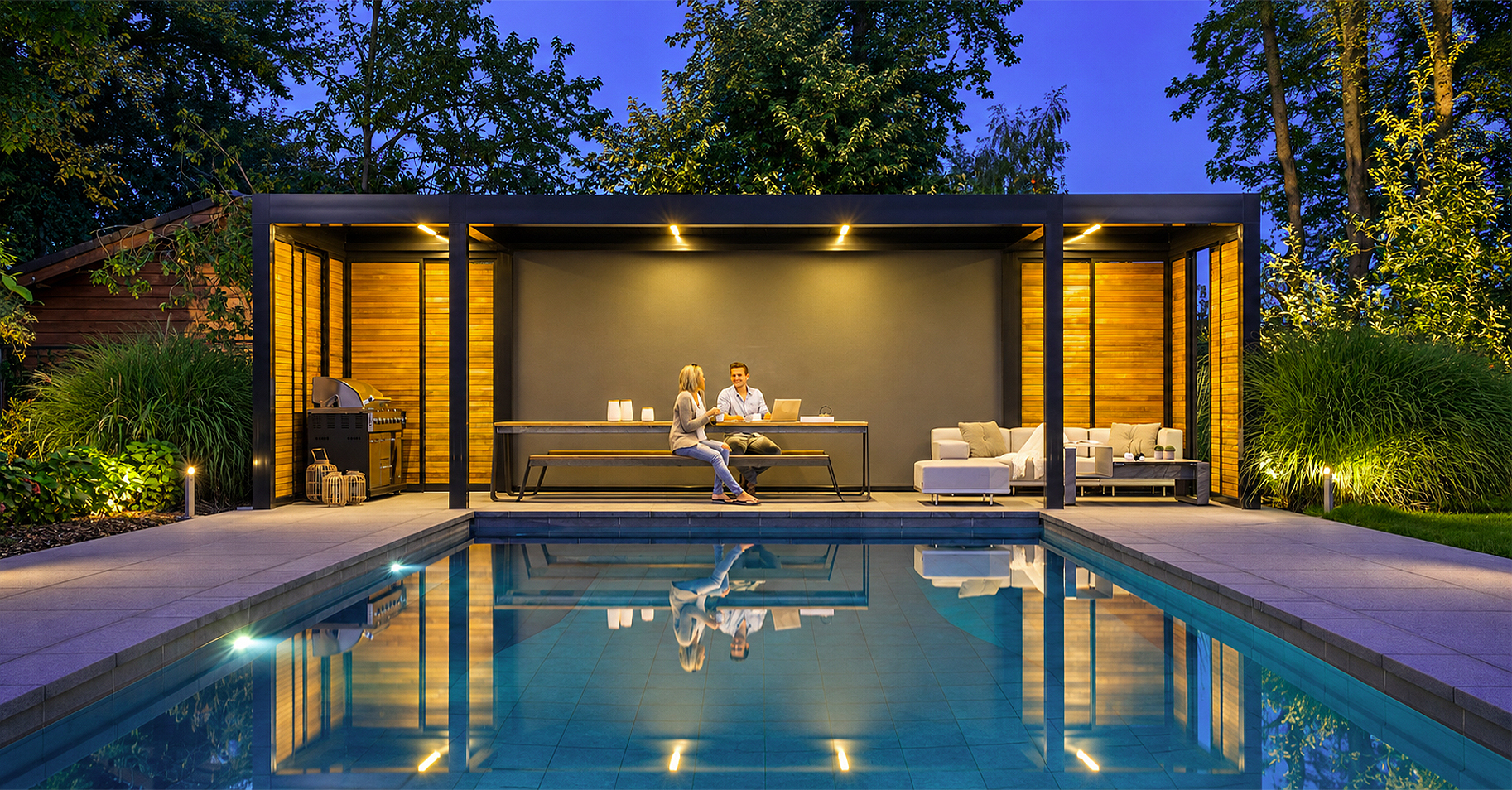 Großzügige Terrassenüberdachung mit beleuchtetem Outdoor-Wohnbereich, Sitzgruppe und Außenküche