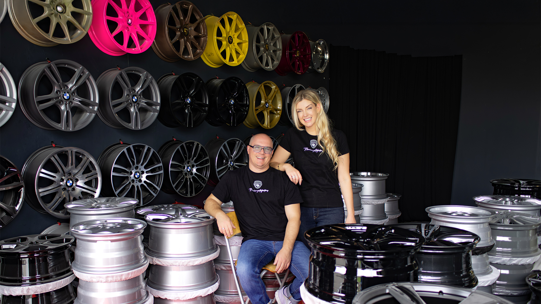 Carmen Seel und ein Mitarbeiter von Originalfelgen24 zwischen aufbereiteten Originalfelgen im Showroom