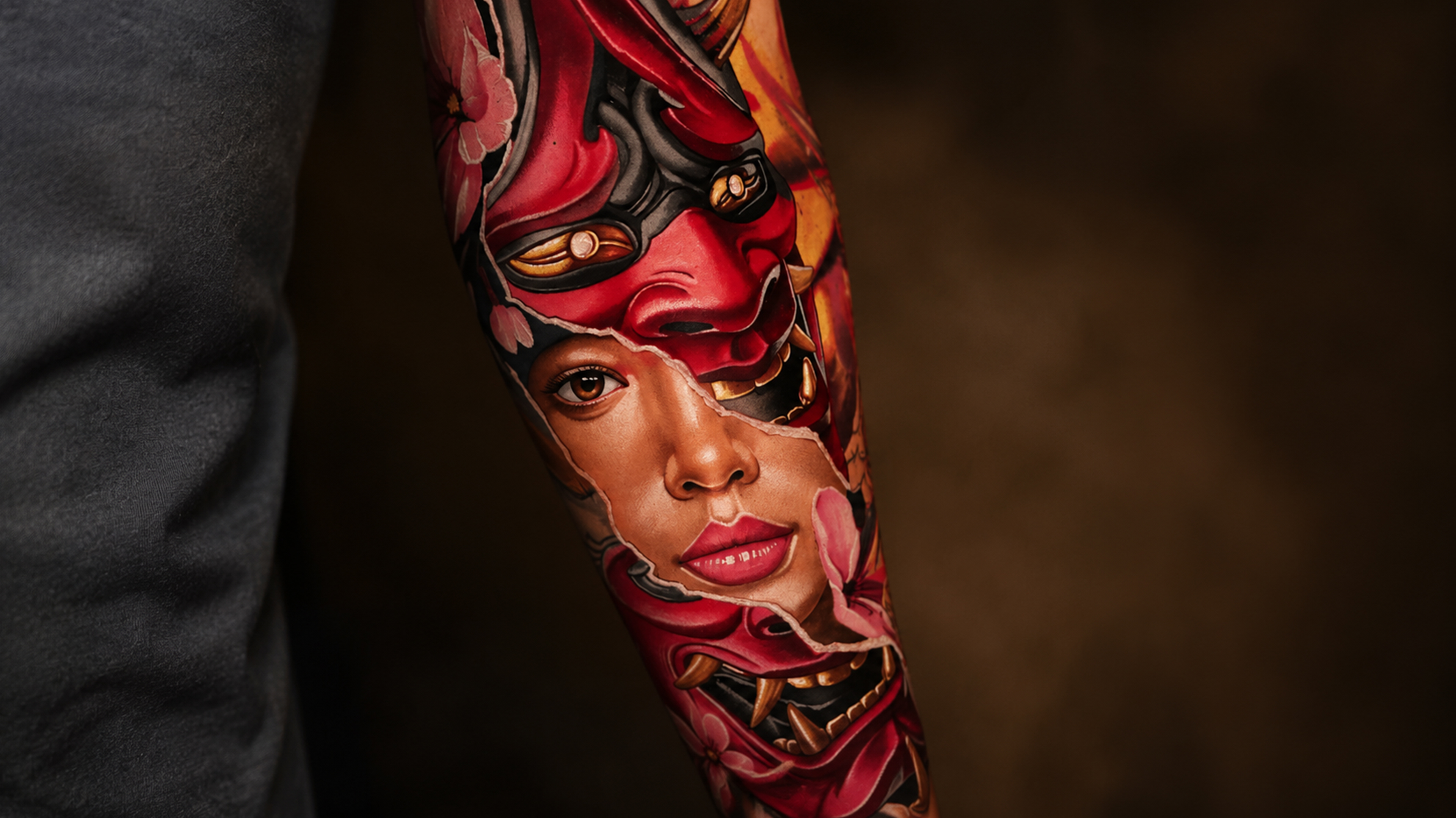 Tattoo am Arm mit rotem und schwarzem Fantasygesicht