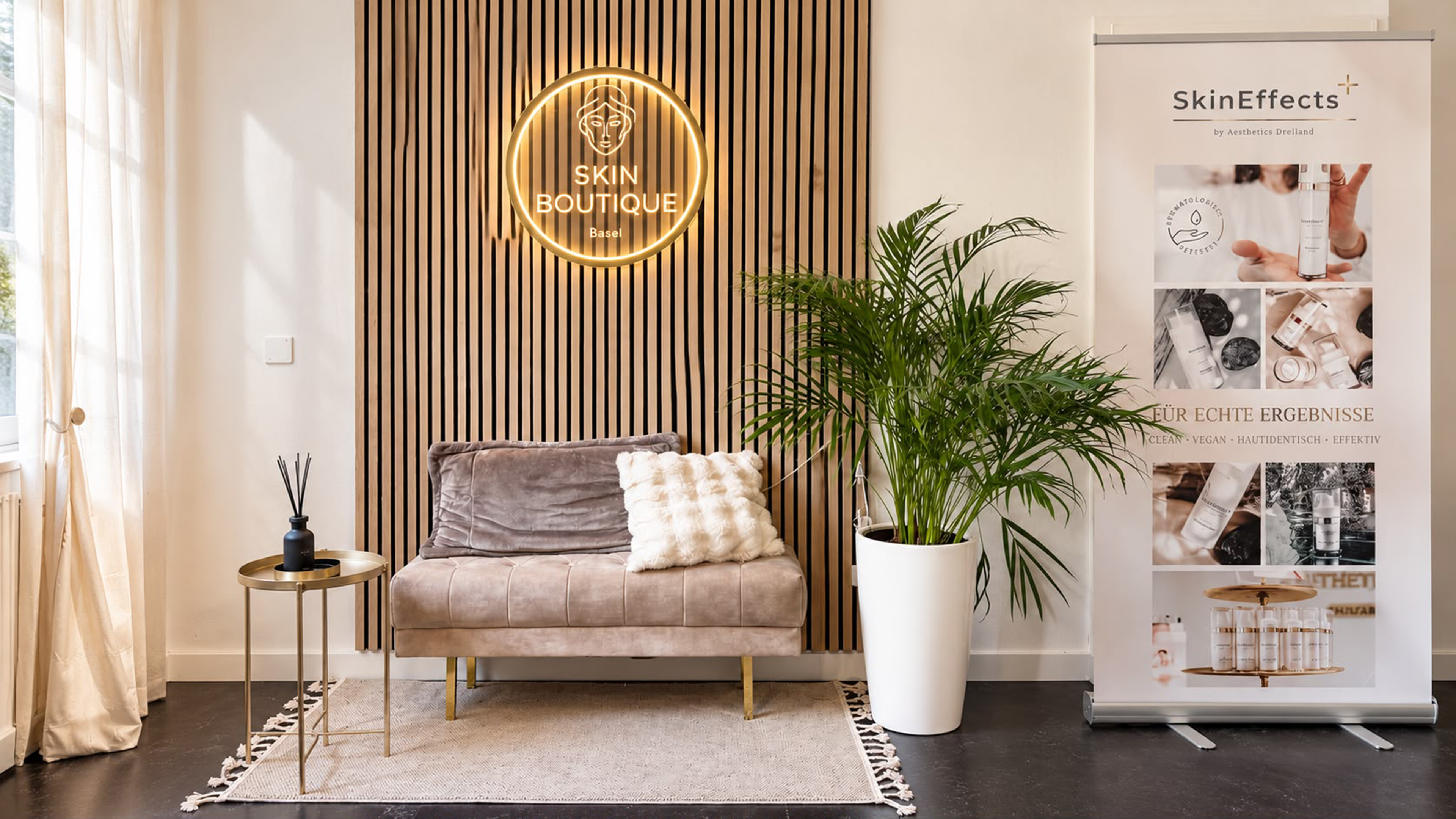 Wartebereich in der Skin Boutique Petra Geiger mit Sitzgelegenheit und Banner