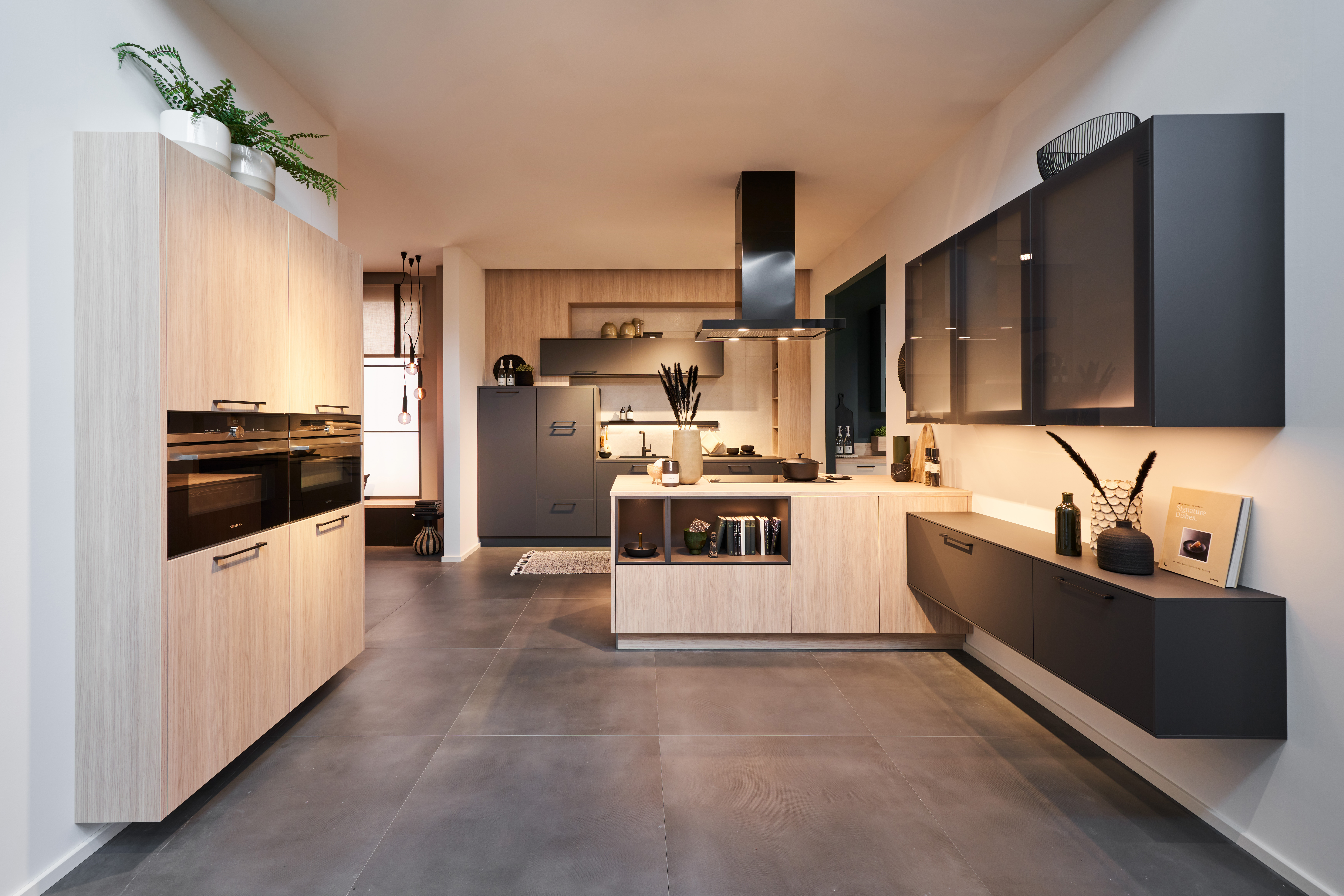 Moderne Einbauküche von di Vinci Kitchen in Jestetten mit hellen Holzfronten, dunklen Hängeschränken und Kochinsel.