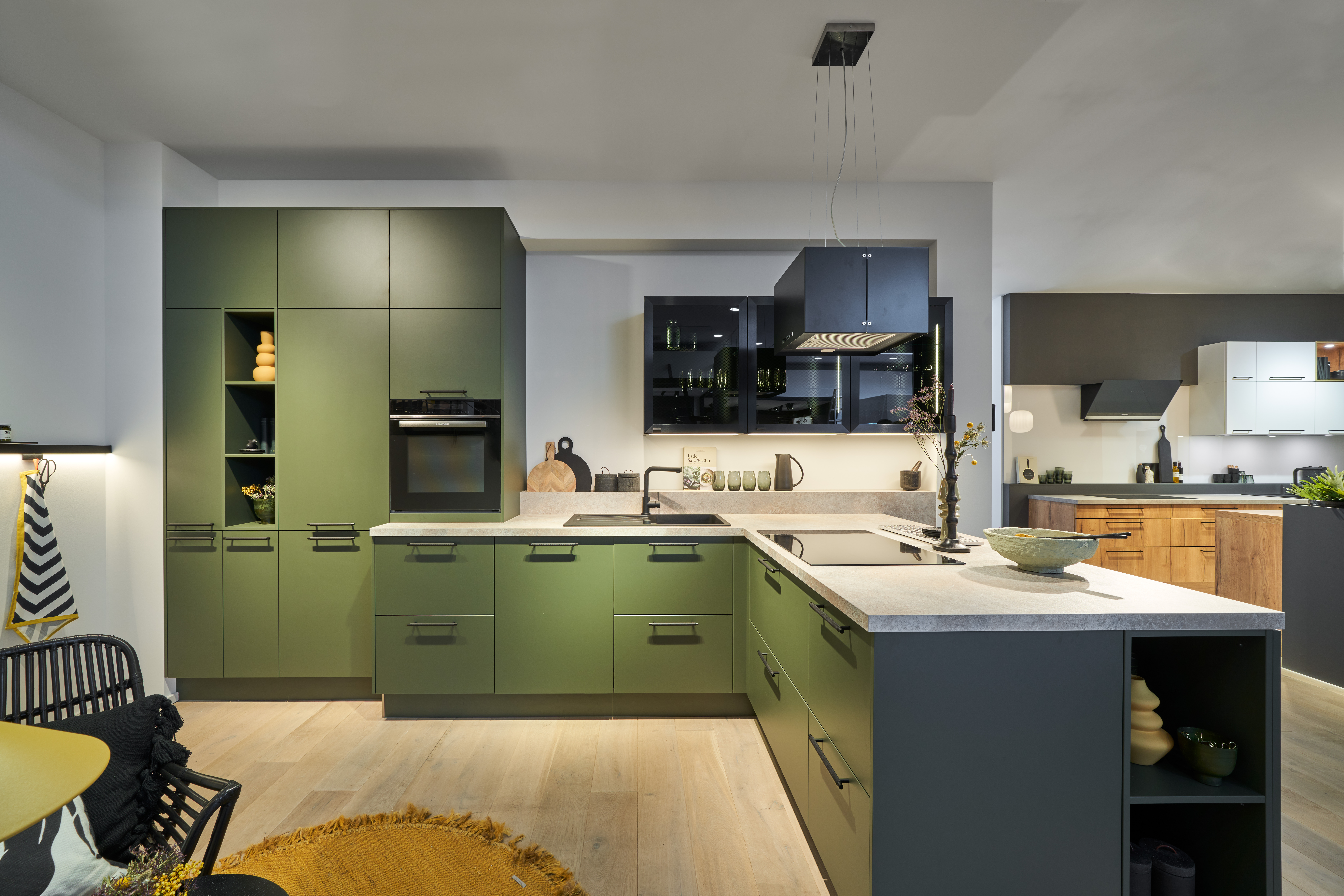 Moderne Schreinerküche nach Maß von di Vinci Kitchen in Jestetten in Mattgrün mit Kochinsel und hellem Holzboden.