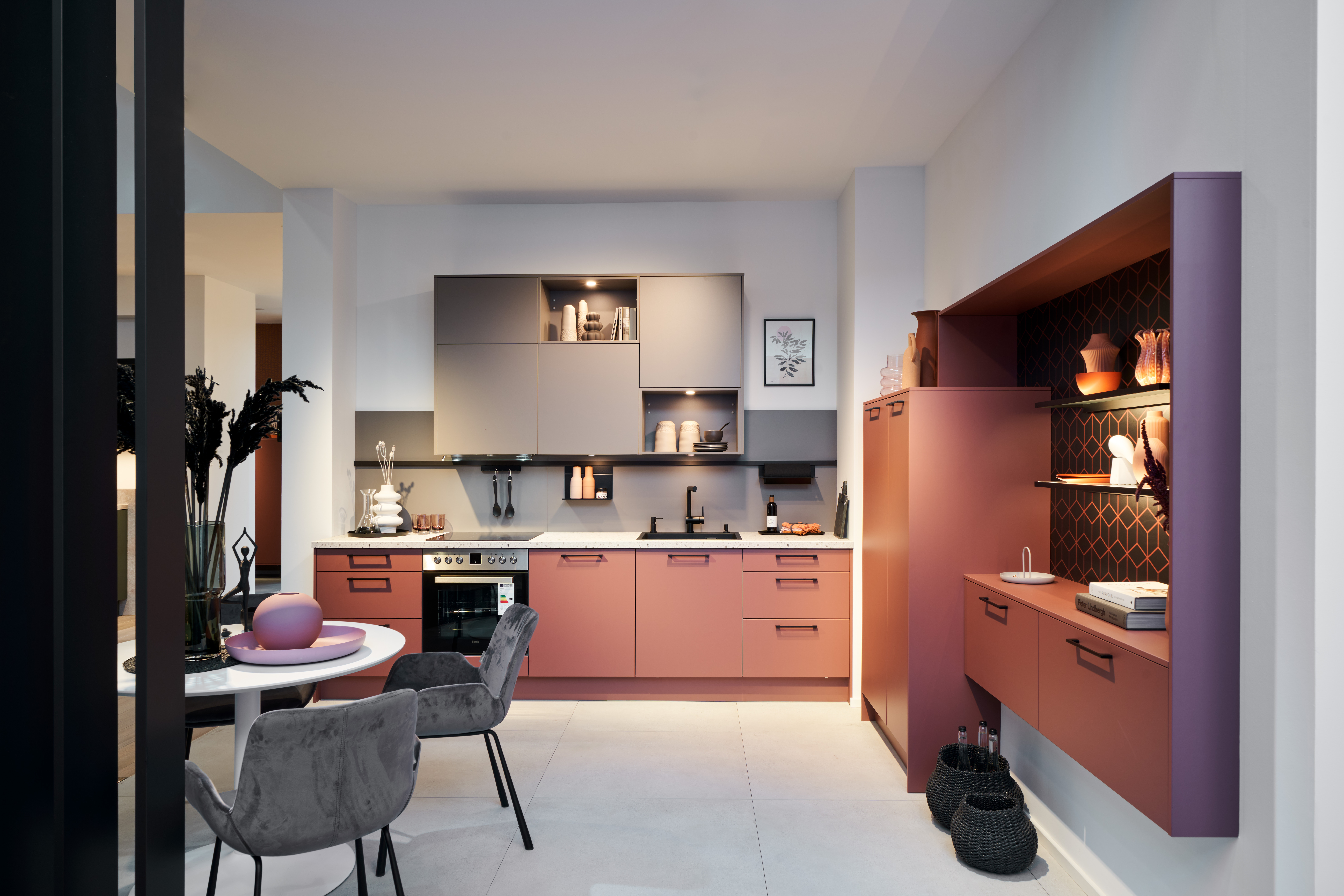 Moderne Schreinerküche nach Maß von di Vinci Kitchen in Jestetten mit terrakottafarbenen Fronten und grauem Esstisch.