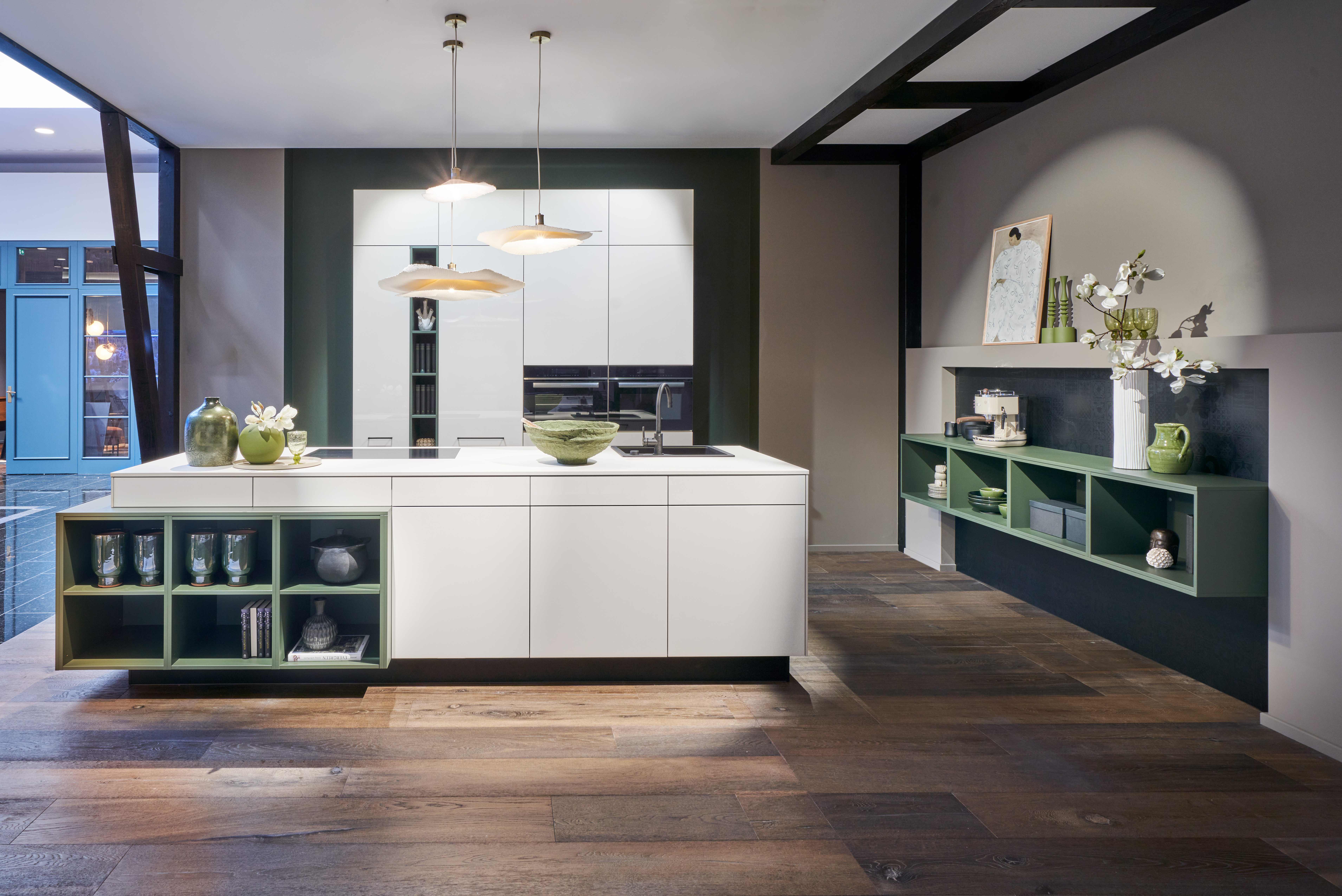 Minimalistische Design-Küche von di Vinci Kitchen in Jestetten mit griffloser weißer Kochinsel und salbeigrünen Akzenten.