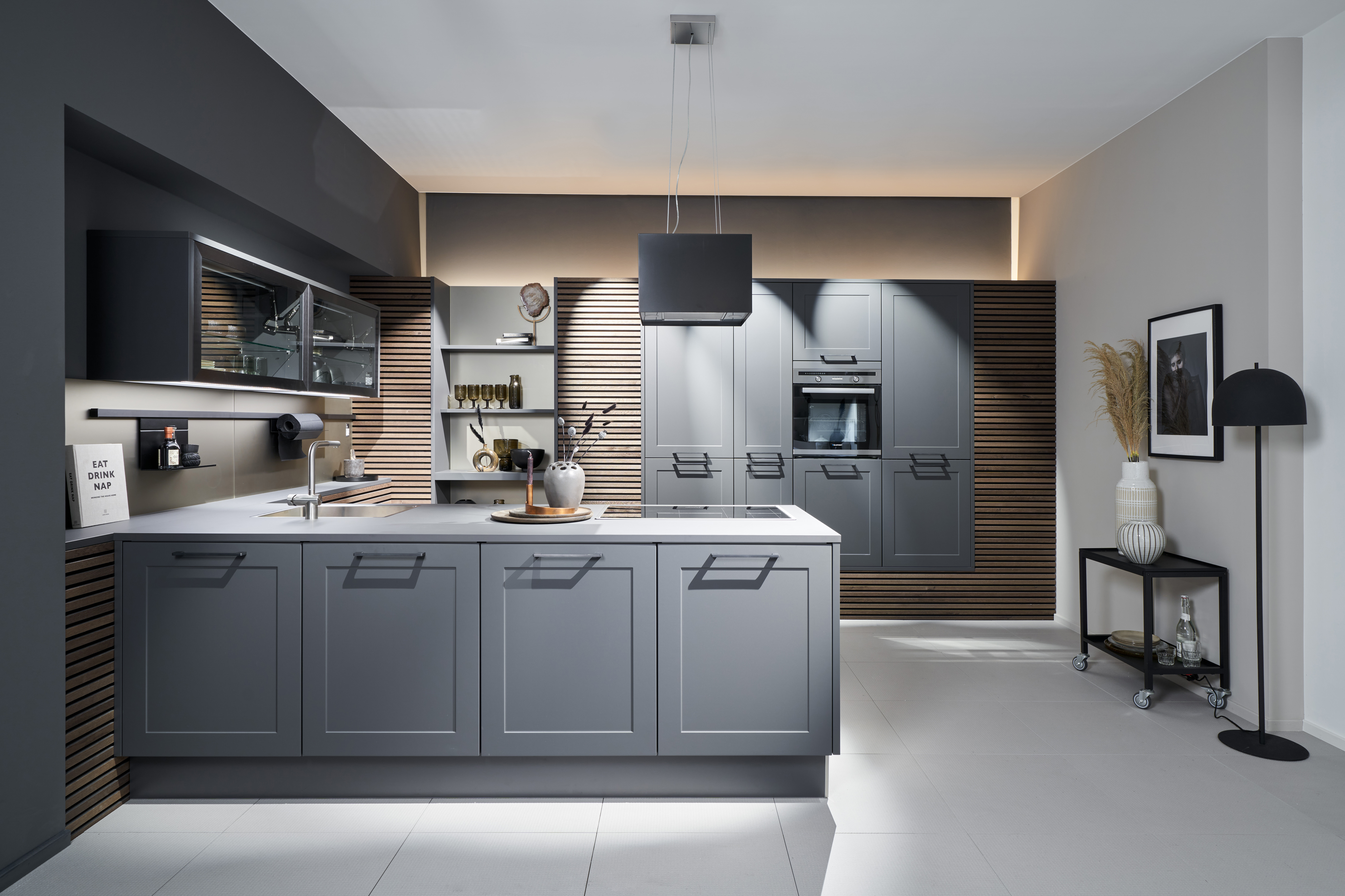 Moderne Design-K&uuml;che von di Vinci Kitchen in Jestetten in elegantem Grau mit Kochinsel und warmen Holzlamellen.
