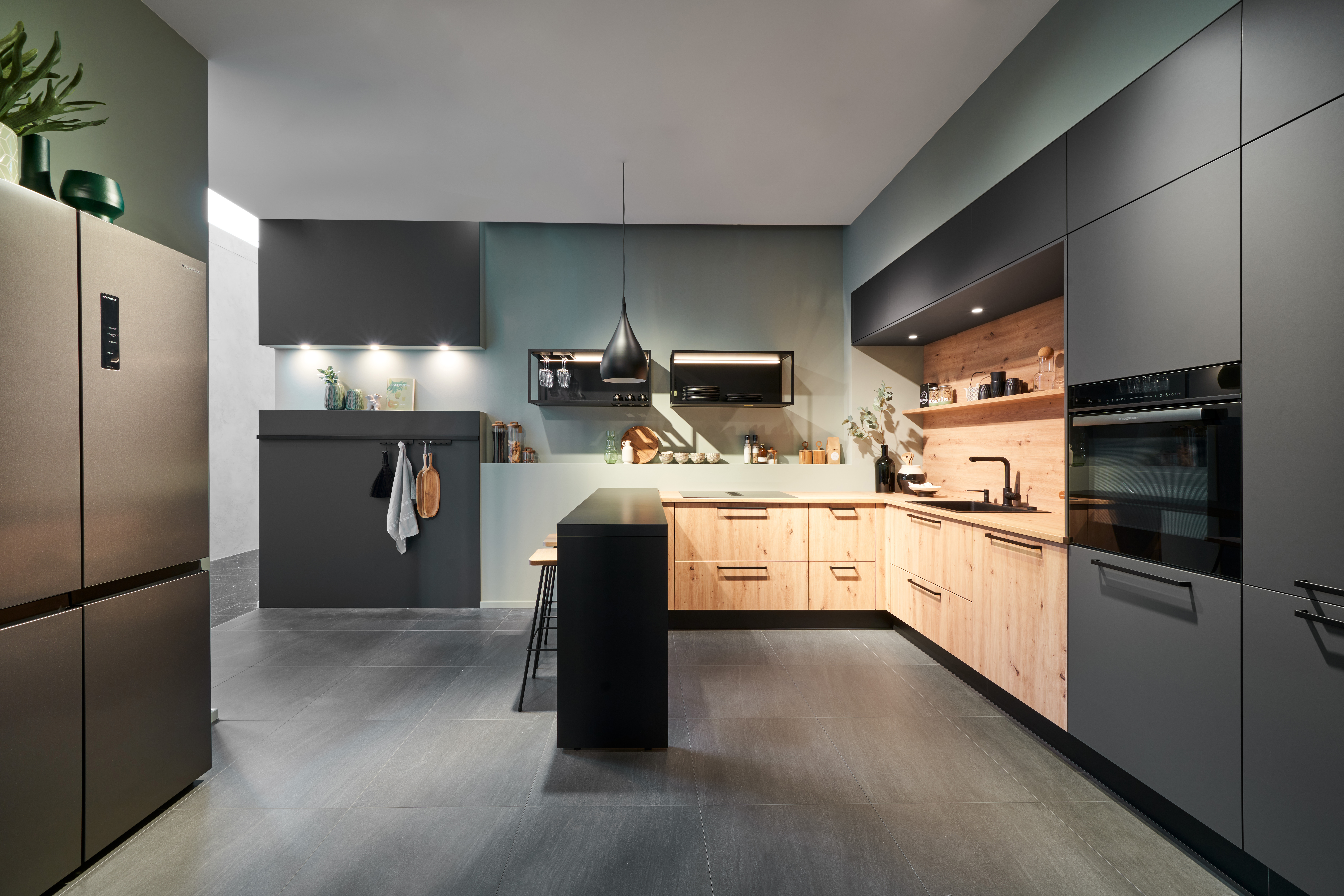 Exklusive Schreinerküche nach Maß von di Vinci Kitchen in Jestetten in Anthrazit mit warmen Holzfronten und Kochinsel.