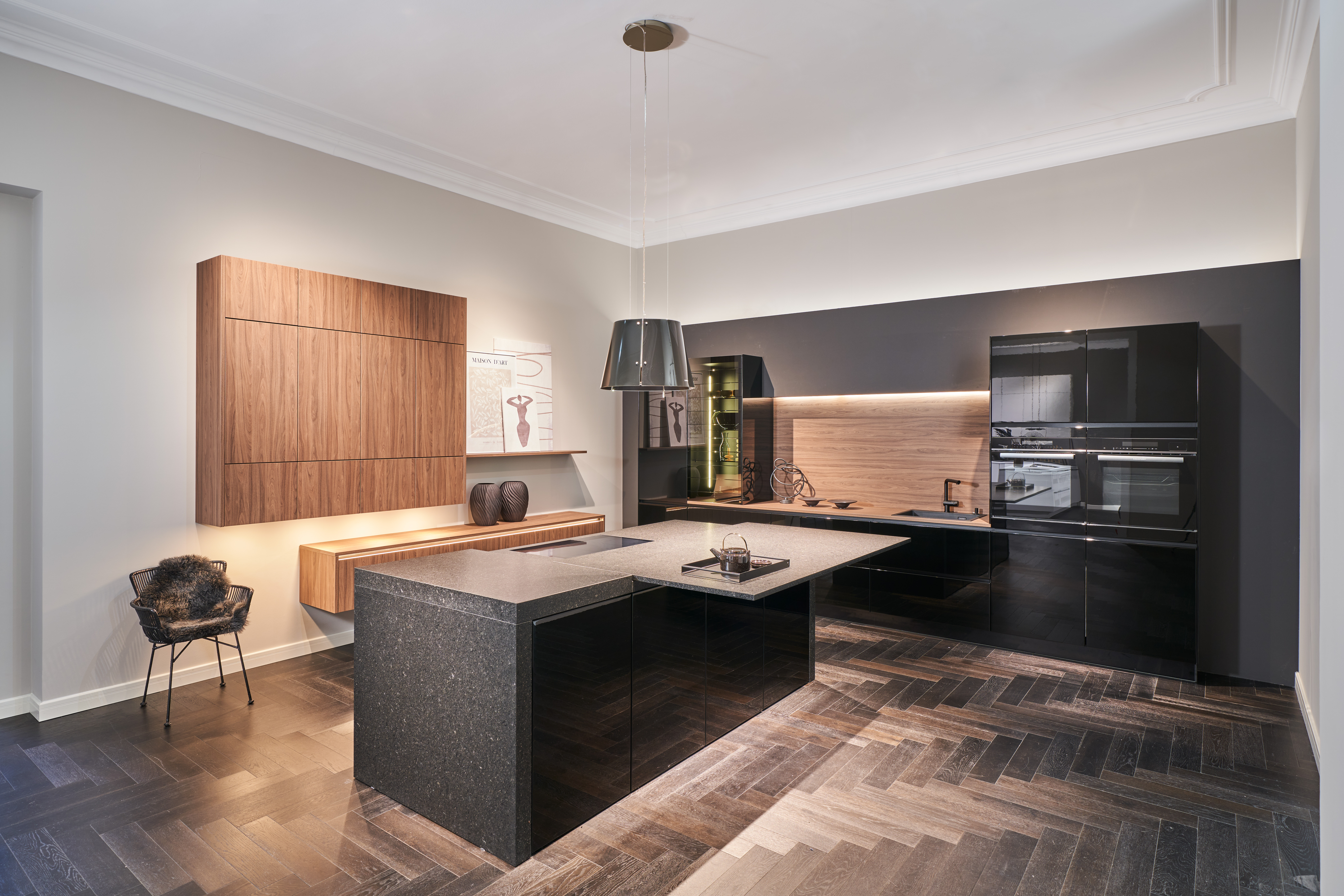Luxus-Küche von di Vinci Kitchen in Jestetten mit schwarzer Kochinsel, Hochglanz-Fronten und Schränken in Holzoptik.