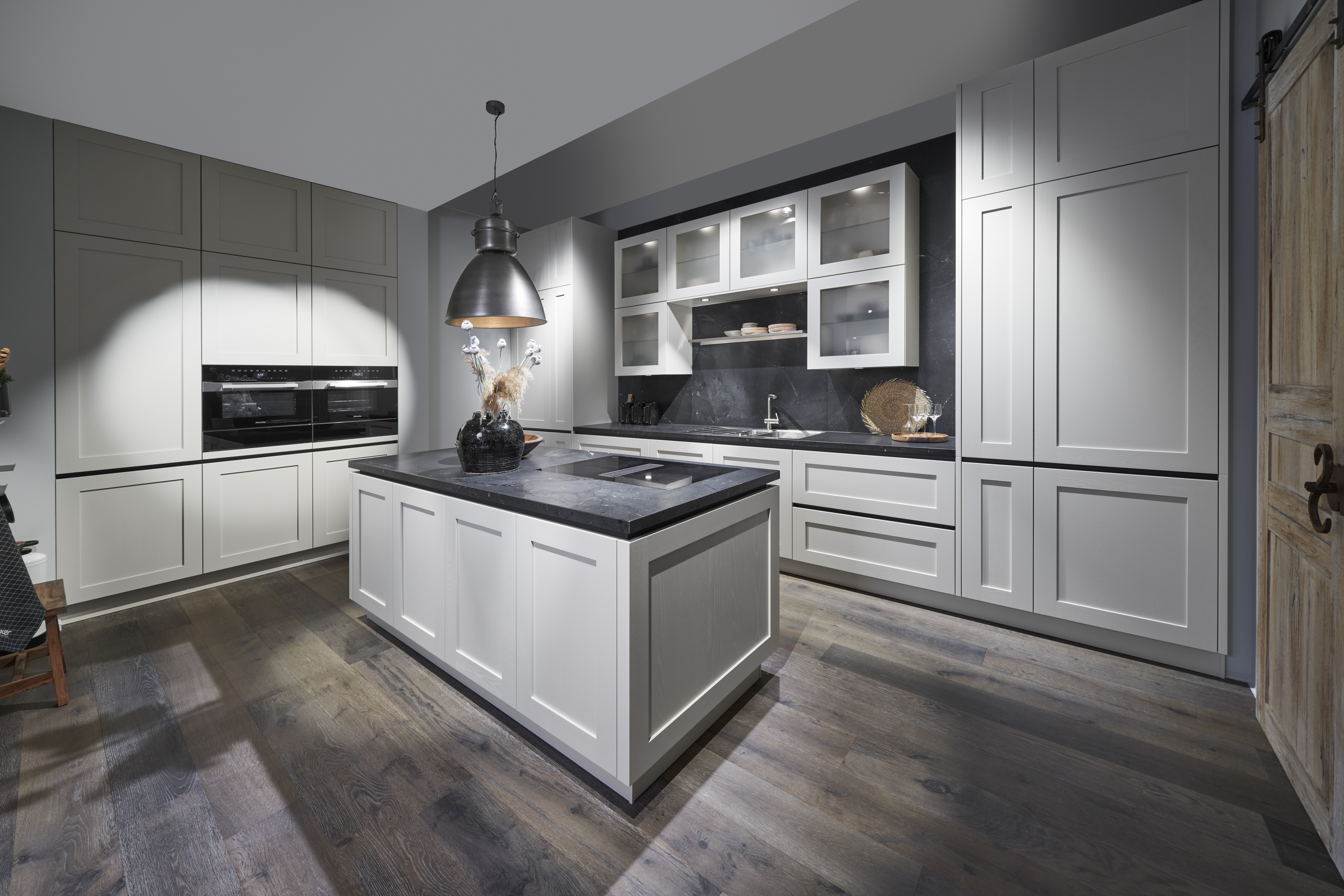 Luxuri&ouml;se K&uuml;che von di Vinci Kitchen in Jestetten mit wei&szlig;er Kochinsel, dunkler Arbeitsplatte und dunklem Holzboden.