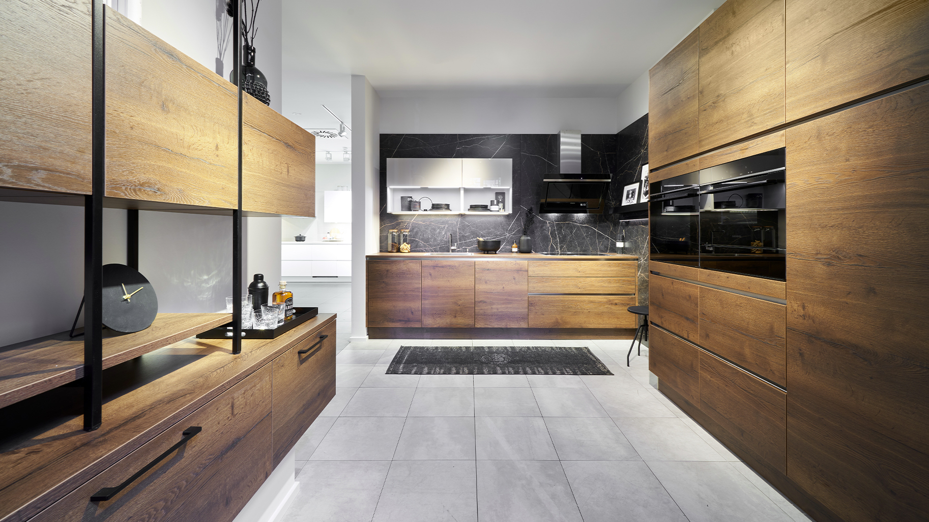 Moderne Küche in Holzoptik von di Vinci Kitchen in Jestetten mit grifflosen Fronten und schwarzer Marmor-Rückwand.