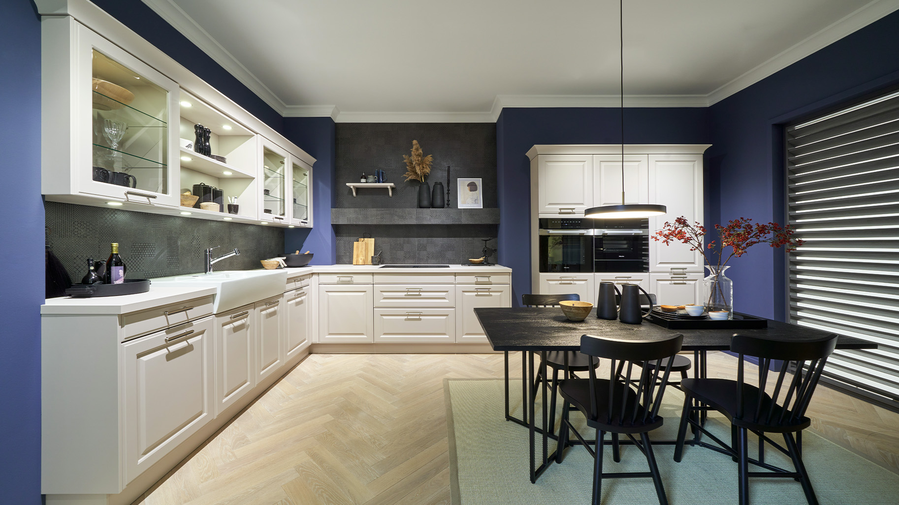 Moderne Landhausk&uuml;che von di Vinci Kitchen in Jestetten mit blauen W&auml;nden, wei&szlig;er Sp&uuml;le und schwarzem Esstisch.