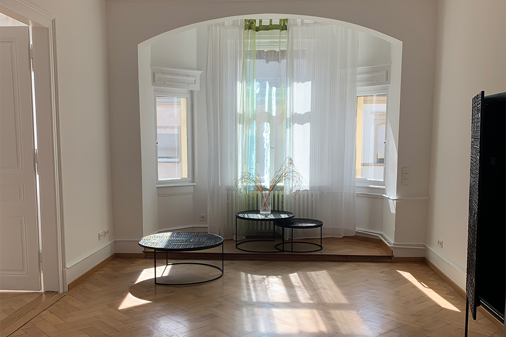 gro&szlig;er Raum mit Holzboden und gro&szlig;en Fenstern