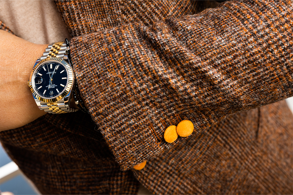 Nahaufnahme von Rolex Uhr und braun gemustertem Massanzug