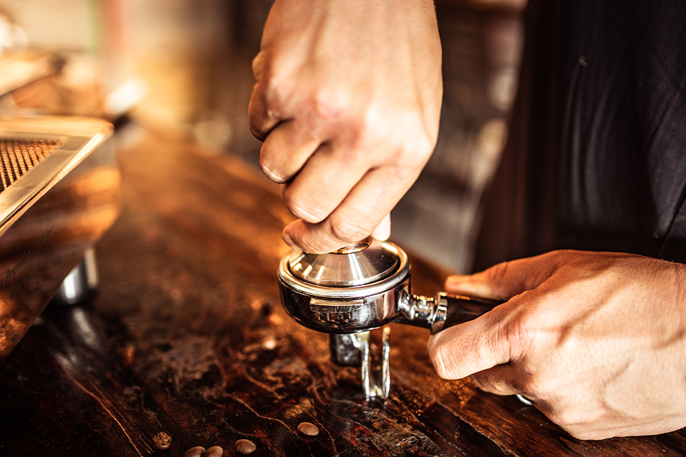 Barista verdichtet Kaffeemehl im Siebträger vor der Espresso-Zubereitung