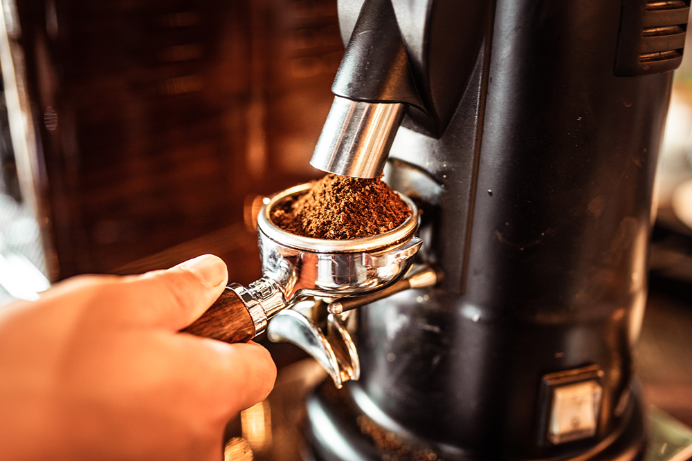 Frisch gemahlener Kaffee fällt aus der Kaffeemühle in einen Siebträger