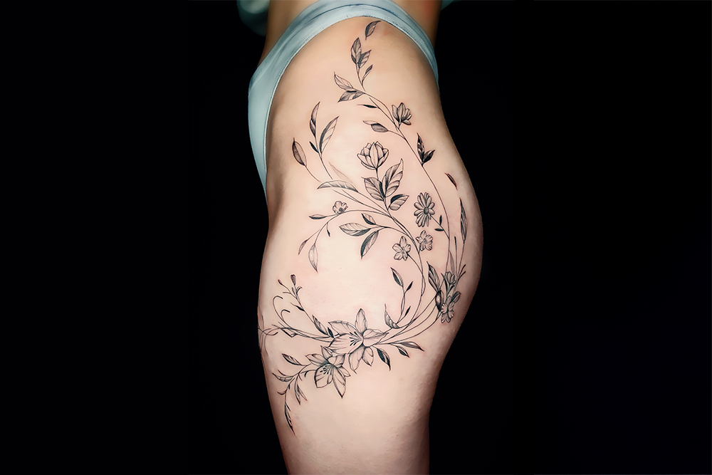 Filigranes Blumen Tattoo an der H&uuml;fte im Fine Line Stil &ndash; &auml;sthetische K&ouml;rperkunst von einem professionellen Tattoo K&uuml;nstler f&uuml;r individuelle Tattoos.