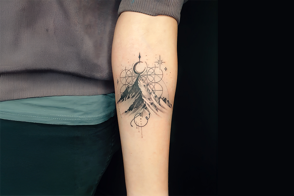 Feines Halbmond Tattoo &uuml;ber Berglandschaft am Unterarm im minimalistischen Fine Line Stil &ndash; pr&auml;zise gestochen im Tattoo Studio.
