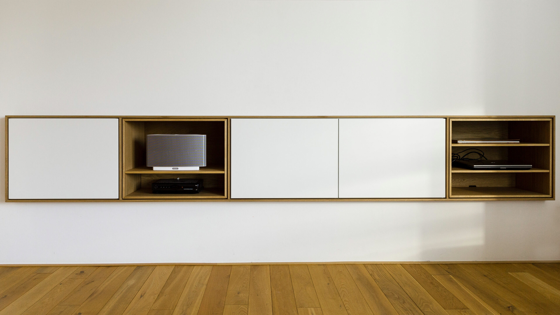 Minimalistisches, h&auml;ngendes Sideboard von Heeg Einrichtungen: Ma&szlig;gefertigtes Design-M&ouml;bel aus Eichenholz mit wei&szlig;en Fronten.