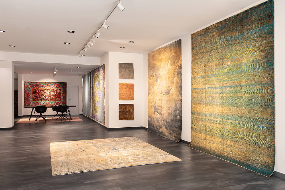 Handgeknüpfte Designteppiche als großformatige Wandobjekte und Bodenfläche in einem modernen Showroom