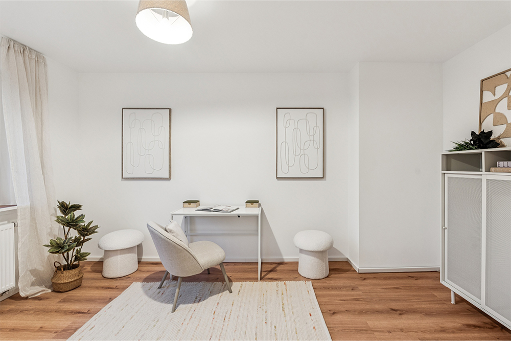 Stilvoll eingerichtetes Home Office mit Schreibtisch, Stuhl, Teppich und dekorativen Bildern &ndash; Beispiel f&uuml;r professionelles Home Staging zur attraktiven Inszenierung einer Wohnung im Immobilienexpos&eacute;.