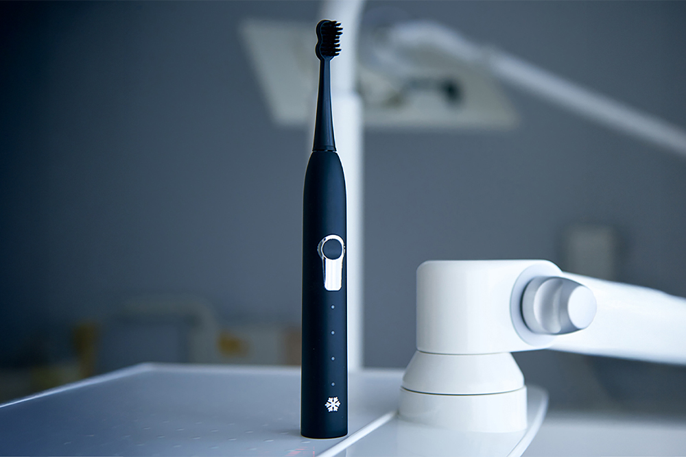Schwarze elektrische SNOW PEARL Schallzahnbürste an einem modernen Waschbecken